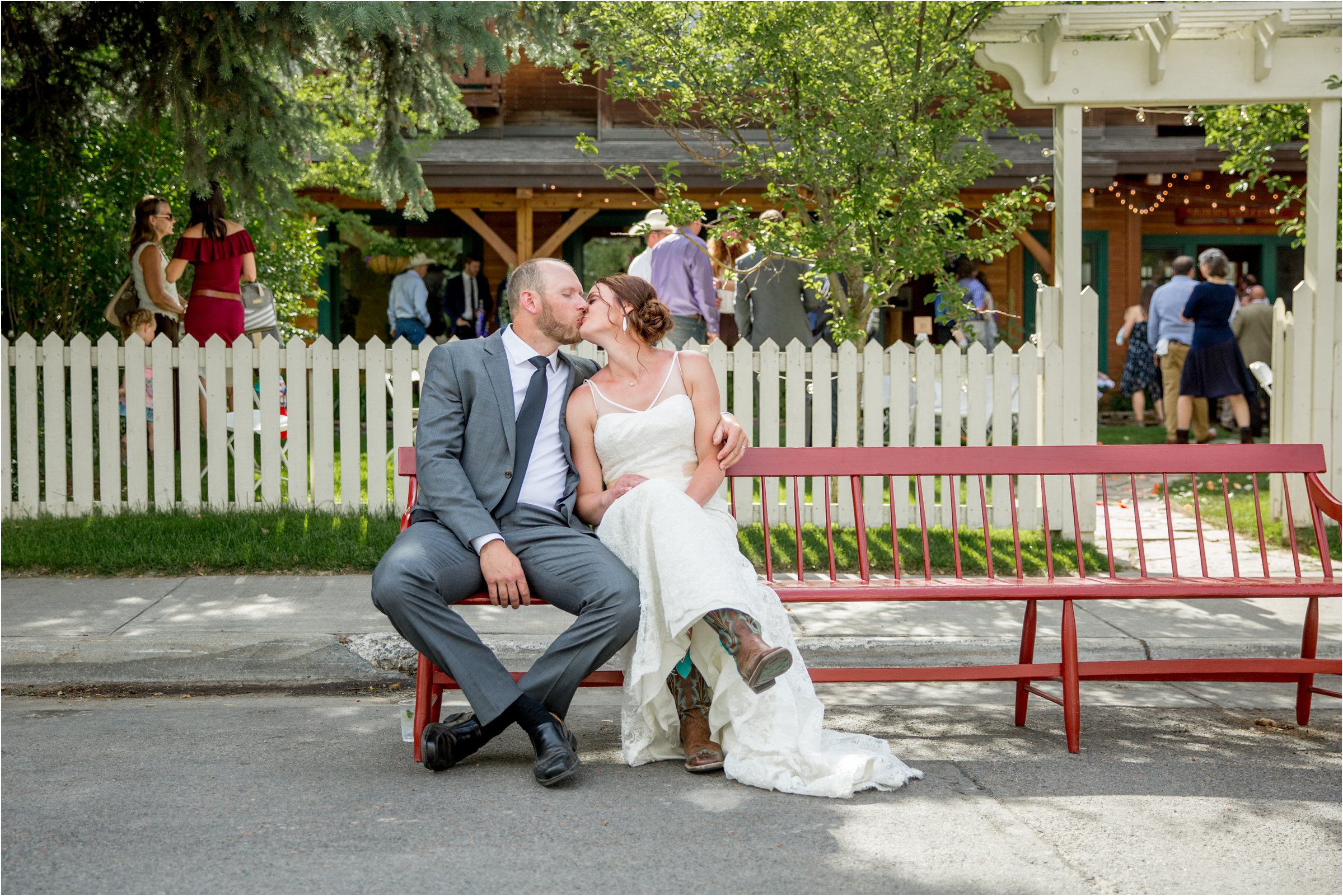 bride and groom sit together on a long bench outside the alpine house in wyoming