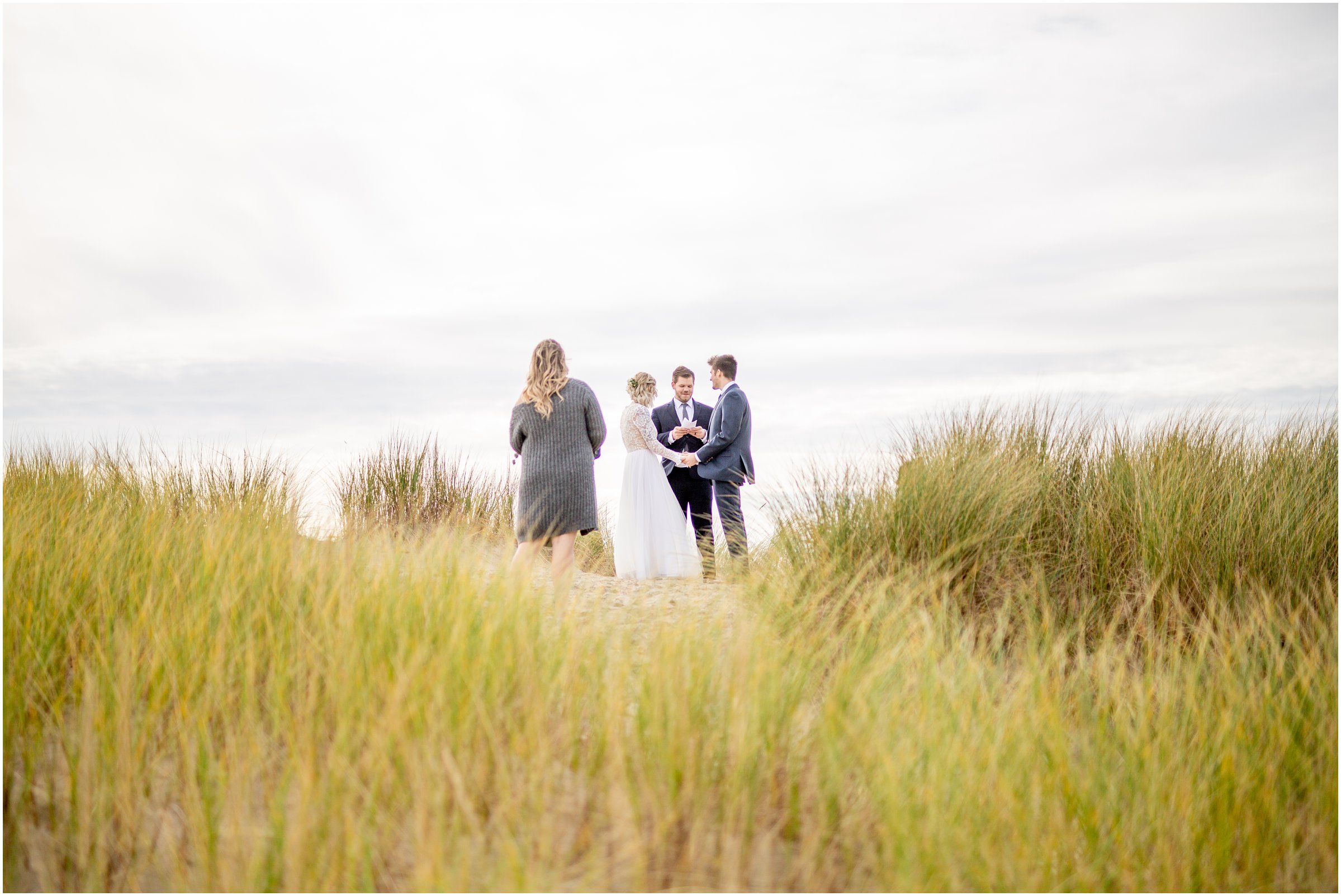 wide shot of bride and groom with officiant and witness on cannon beach during their elopement