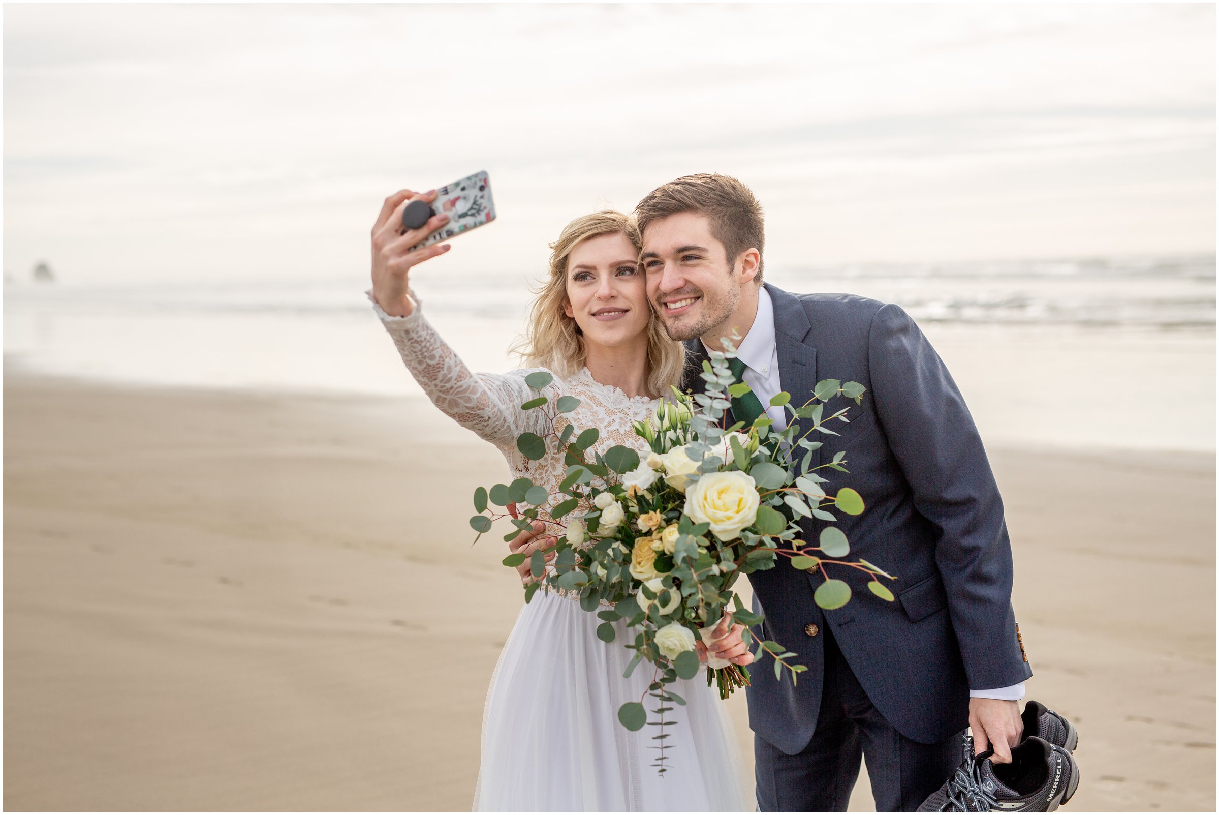 bride and groom take a selfie together on cannon beach after getting married
