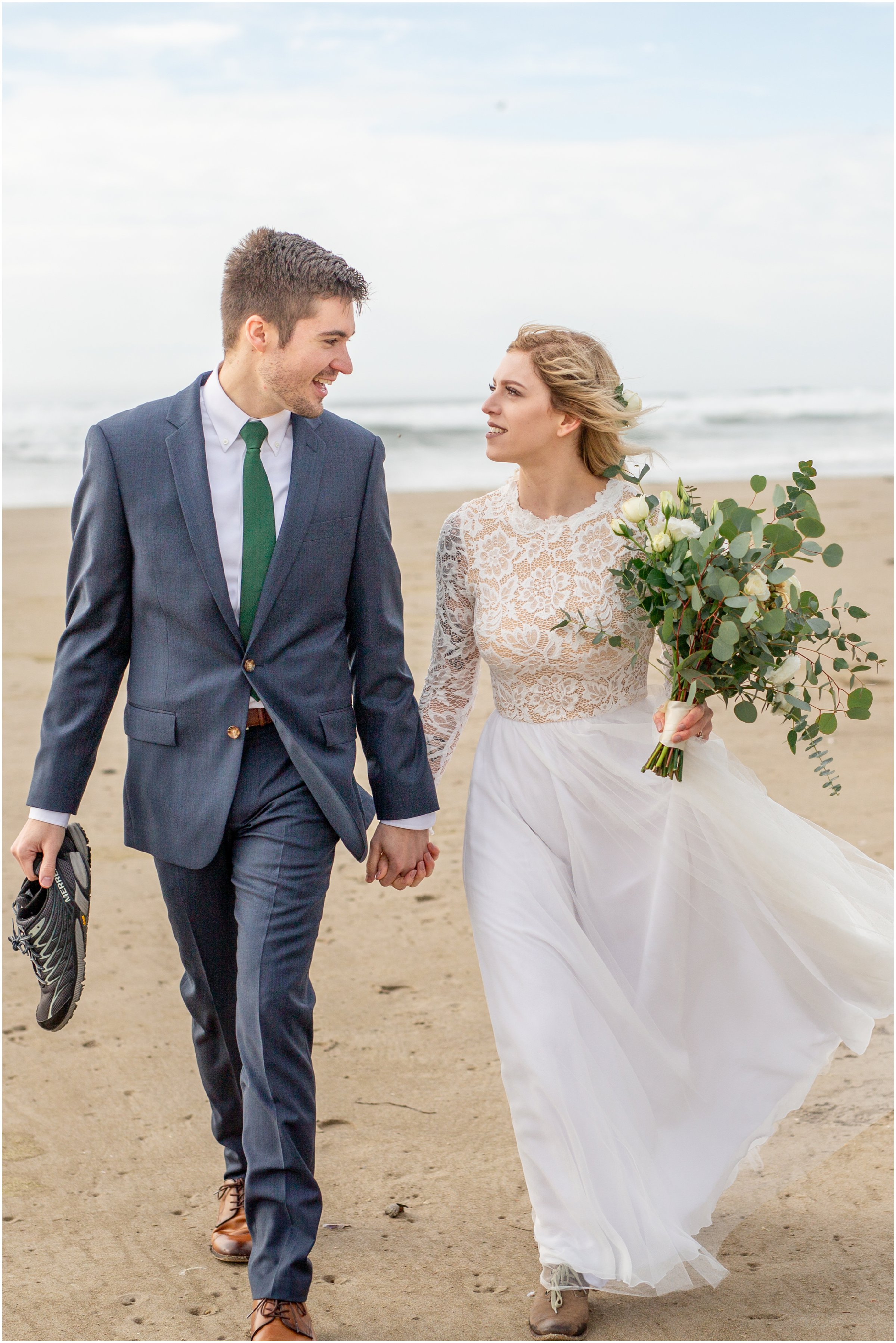 bride and groom walking down cannon beach together after their elopement
