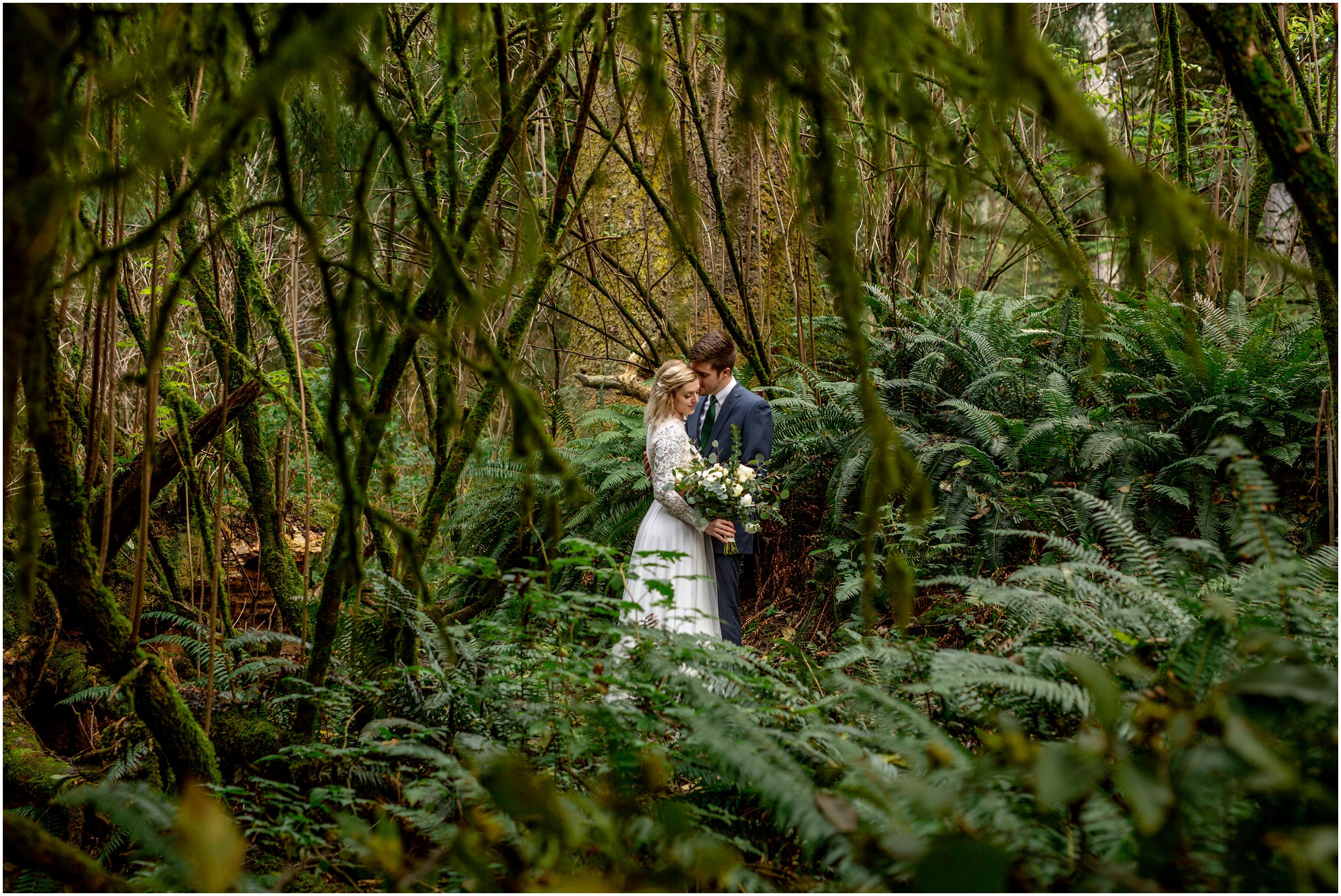 bride and groom snuggle together in ecola state park with ferns surrounding them