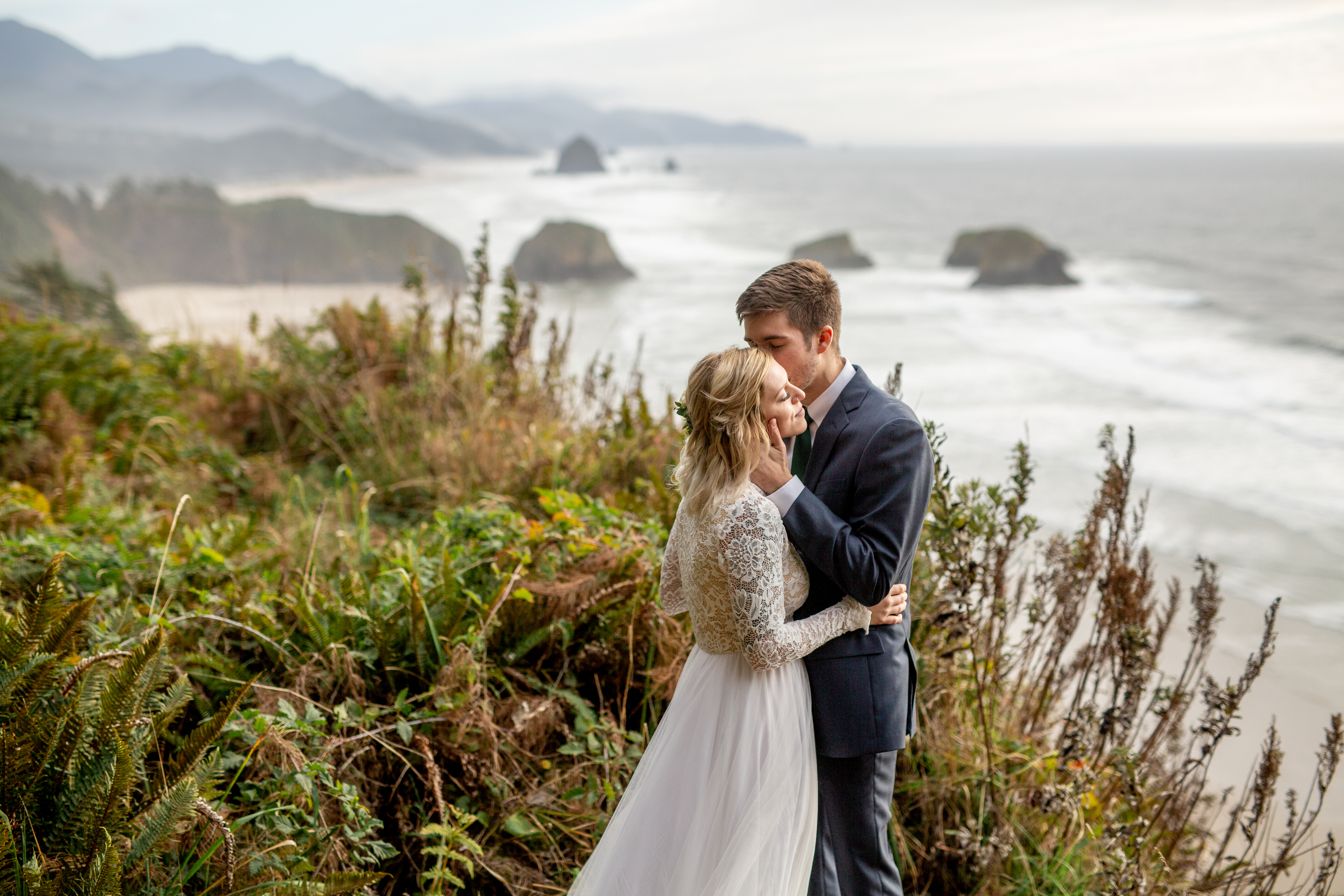 bride and groom overlooking the beach in ecola state park after their wedding