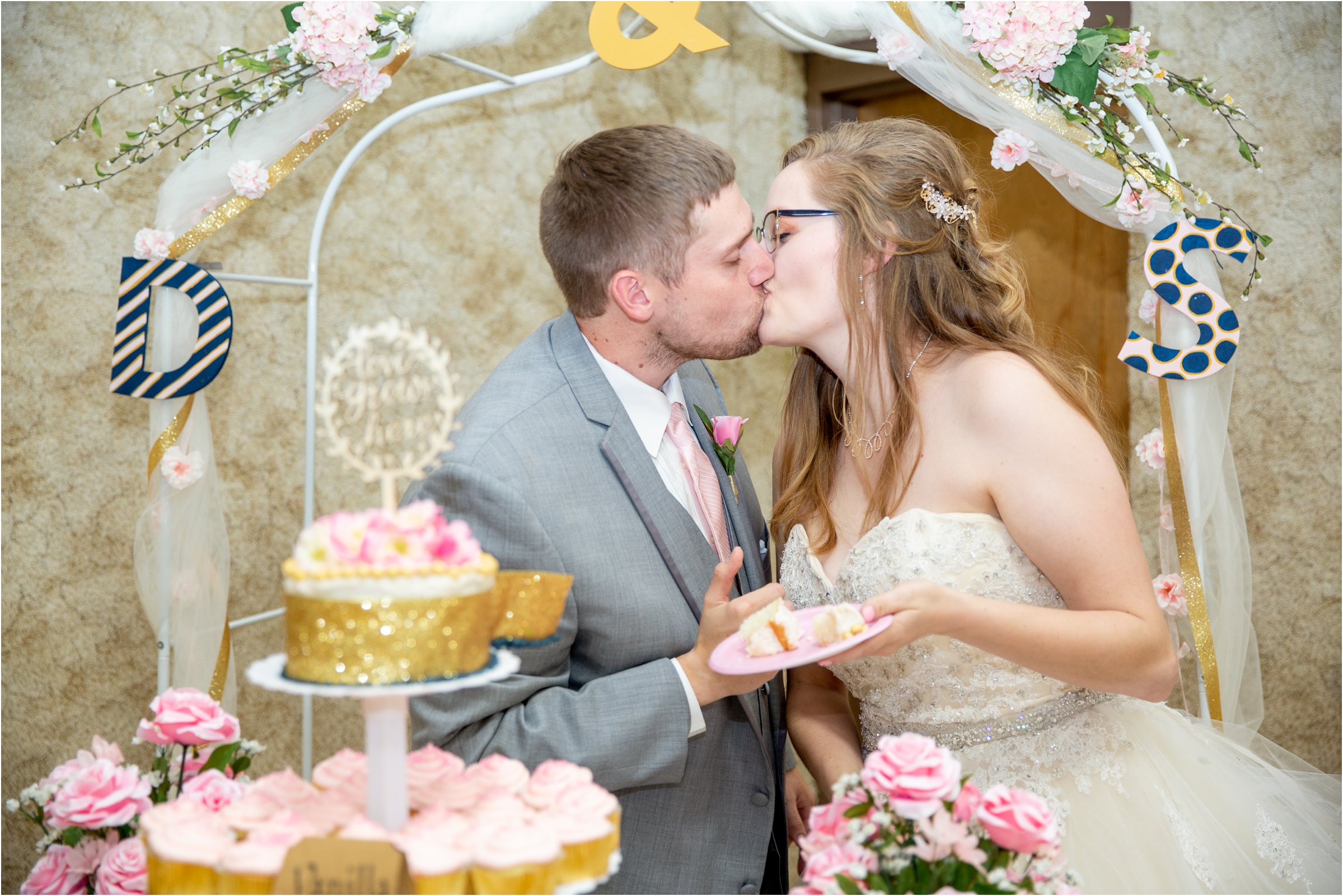 bride and groom kiss after sharing a first bite of their wedding cake at holdrege trinity church