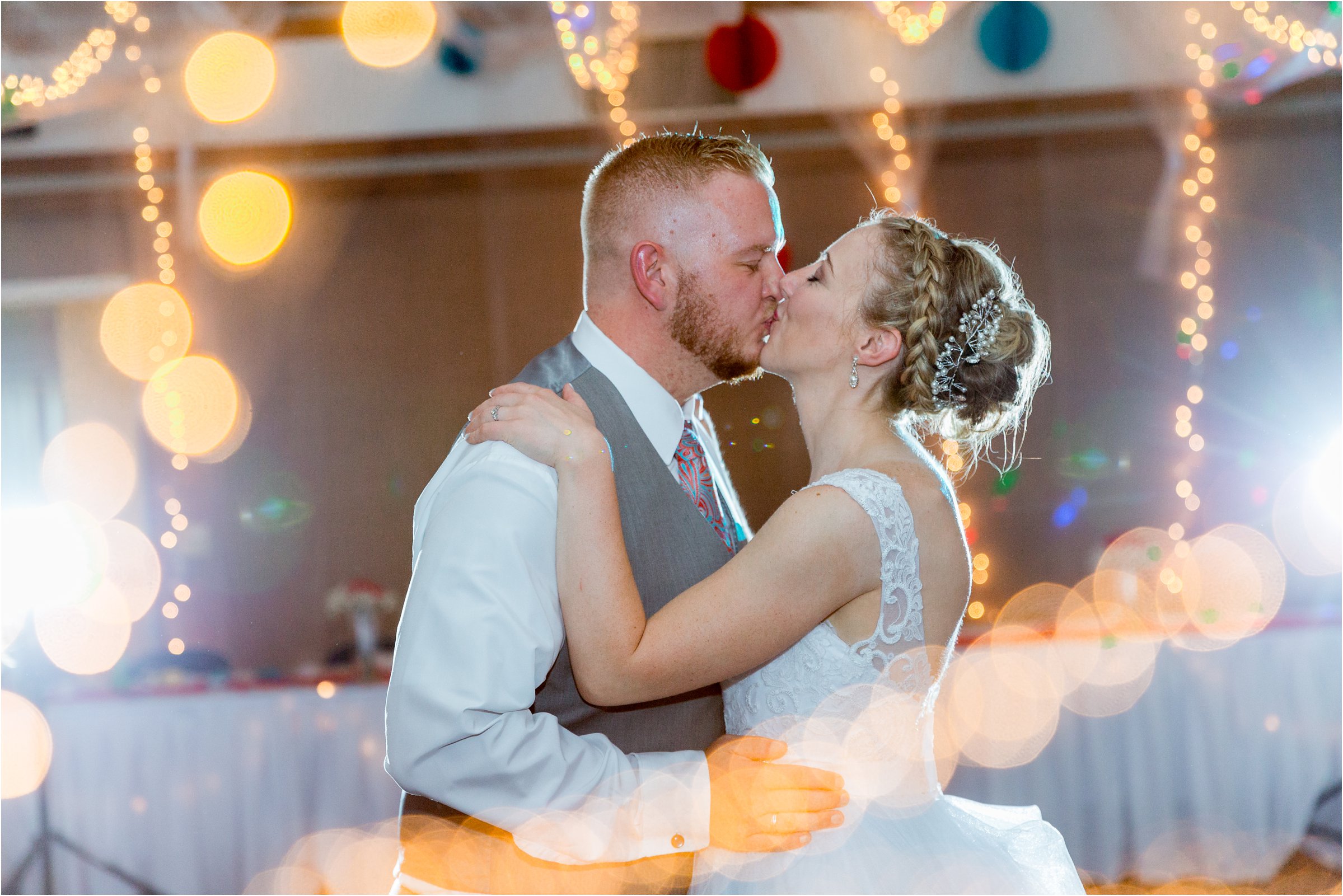 bride and groom kiss under lights at their wedding reception