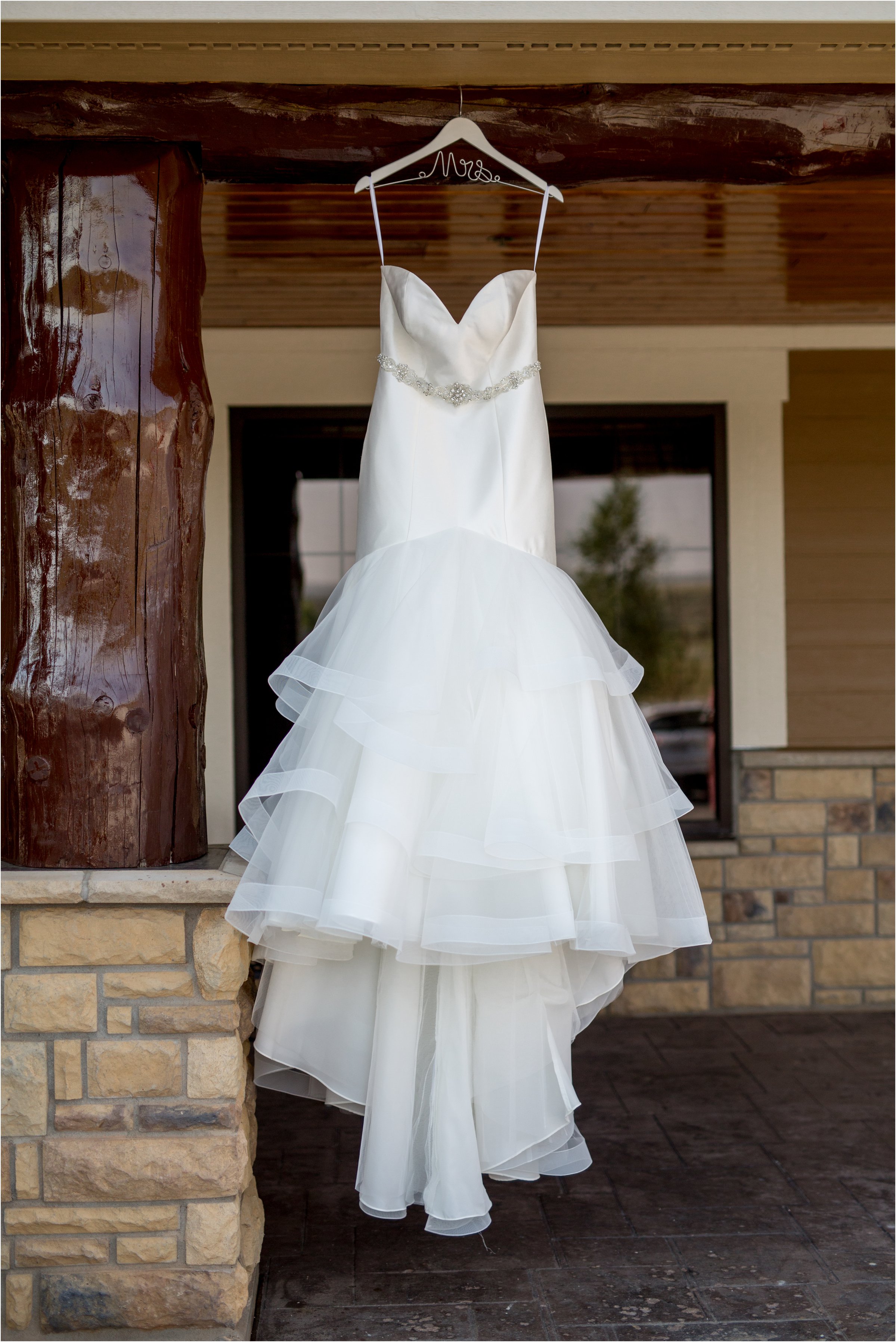 bride's wedding dress hanging on a rustic looking log outside a laramie hotel