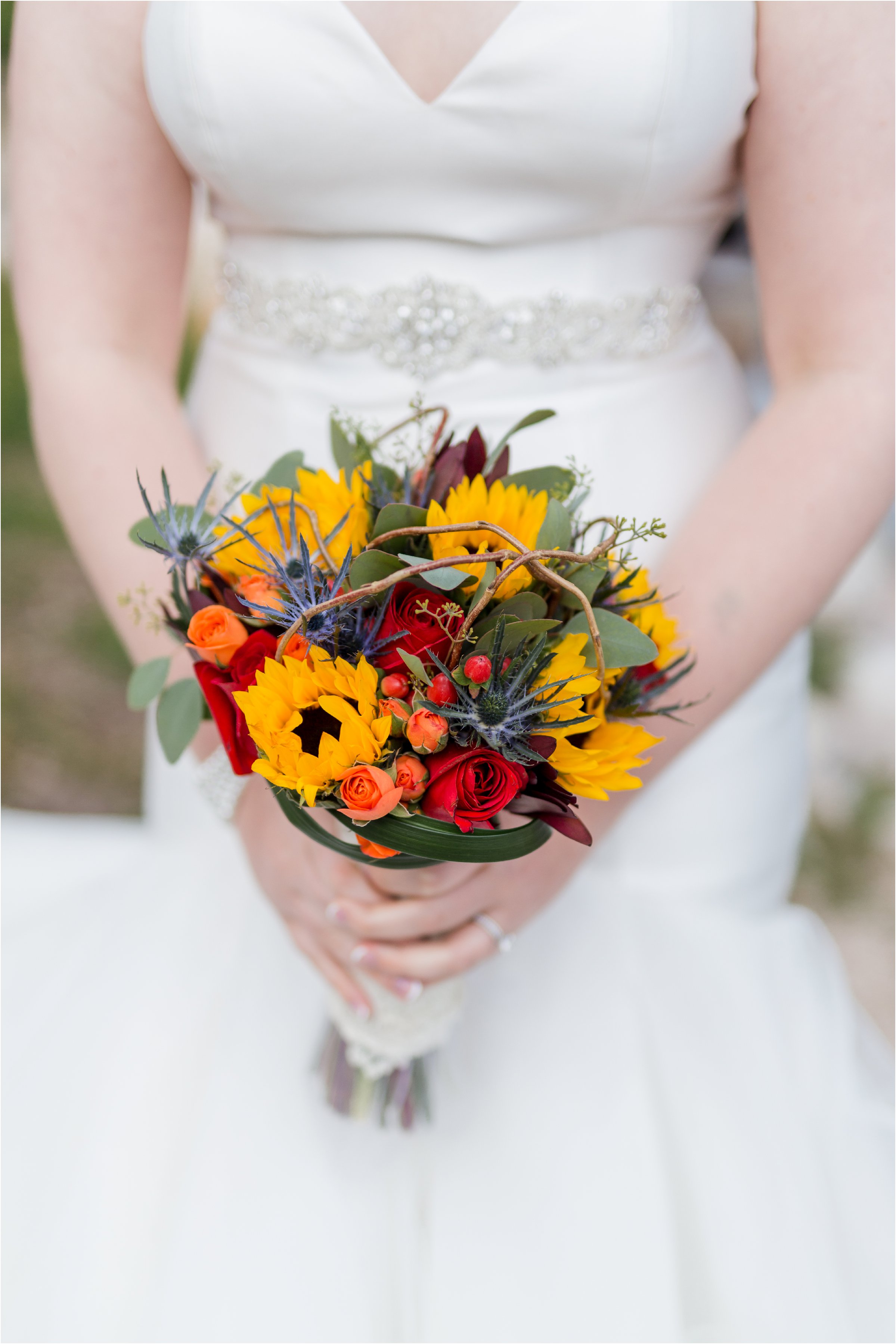 bride's bouquet made up of sunflowers, red roses, and whild flowers along with twigs