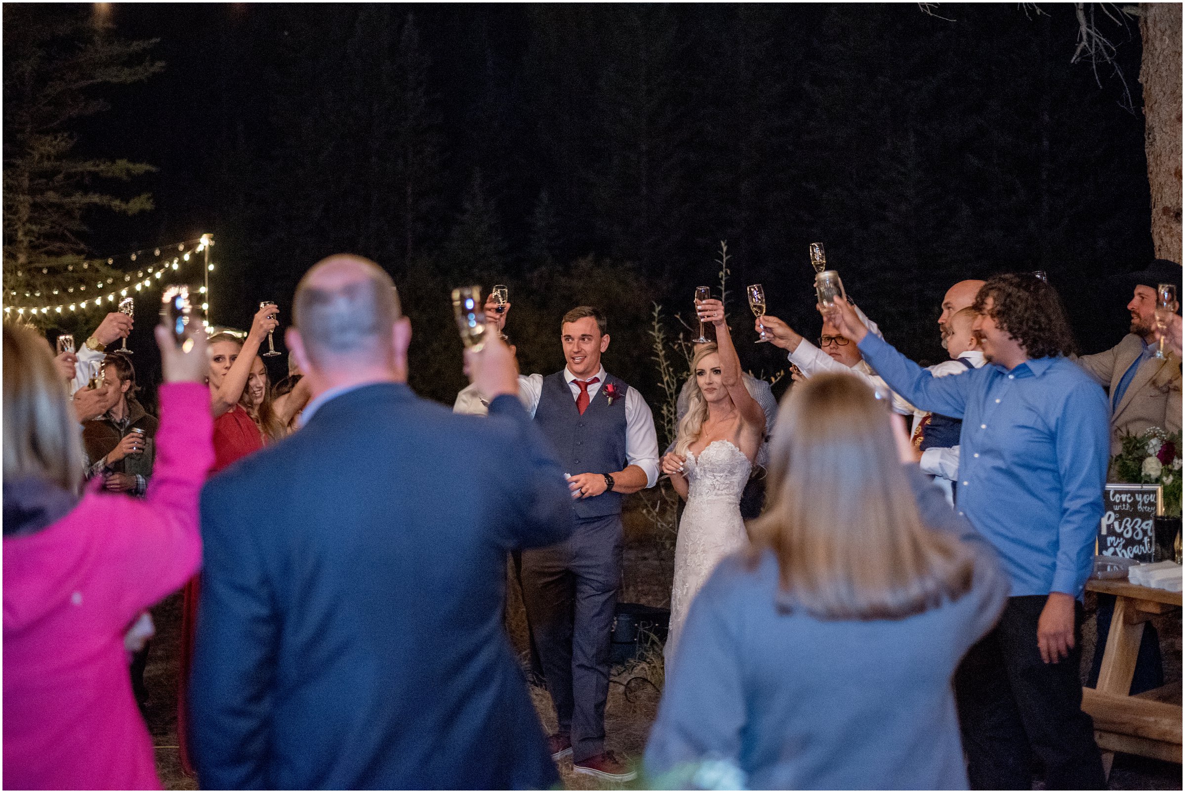 guests toast the bride and groom at their outdoor reception next to the creek