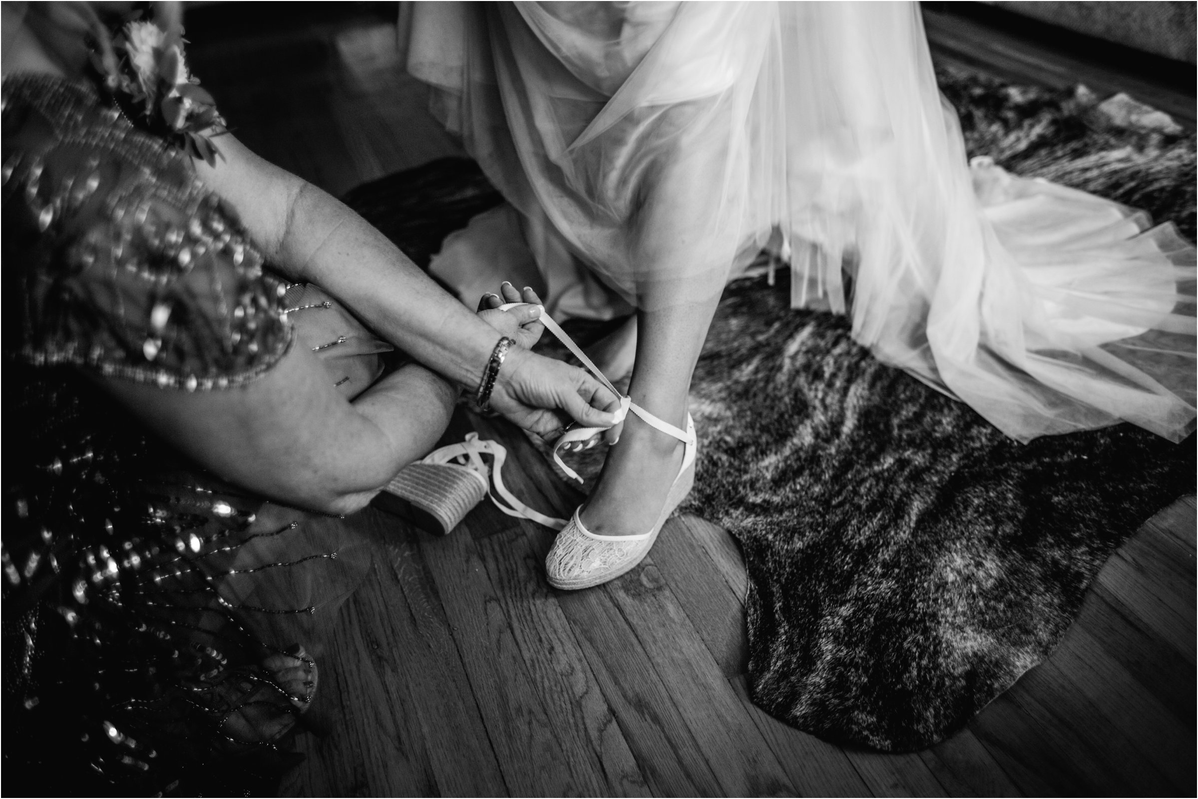 the bride's mom helping her into her dress in her own living room
