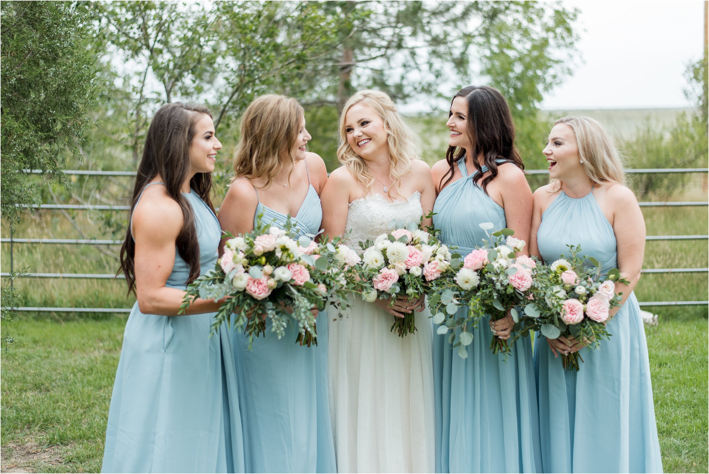 the bridesmaids dressed in light blue hold their bouquets and look toward the bride