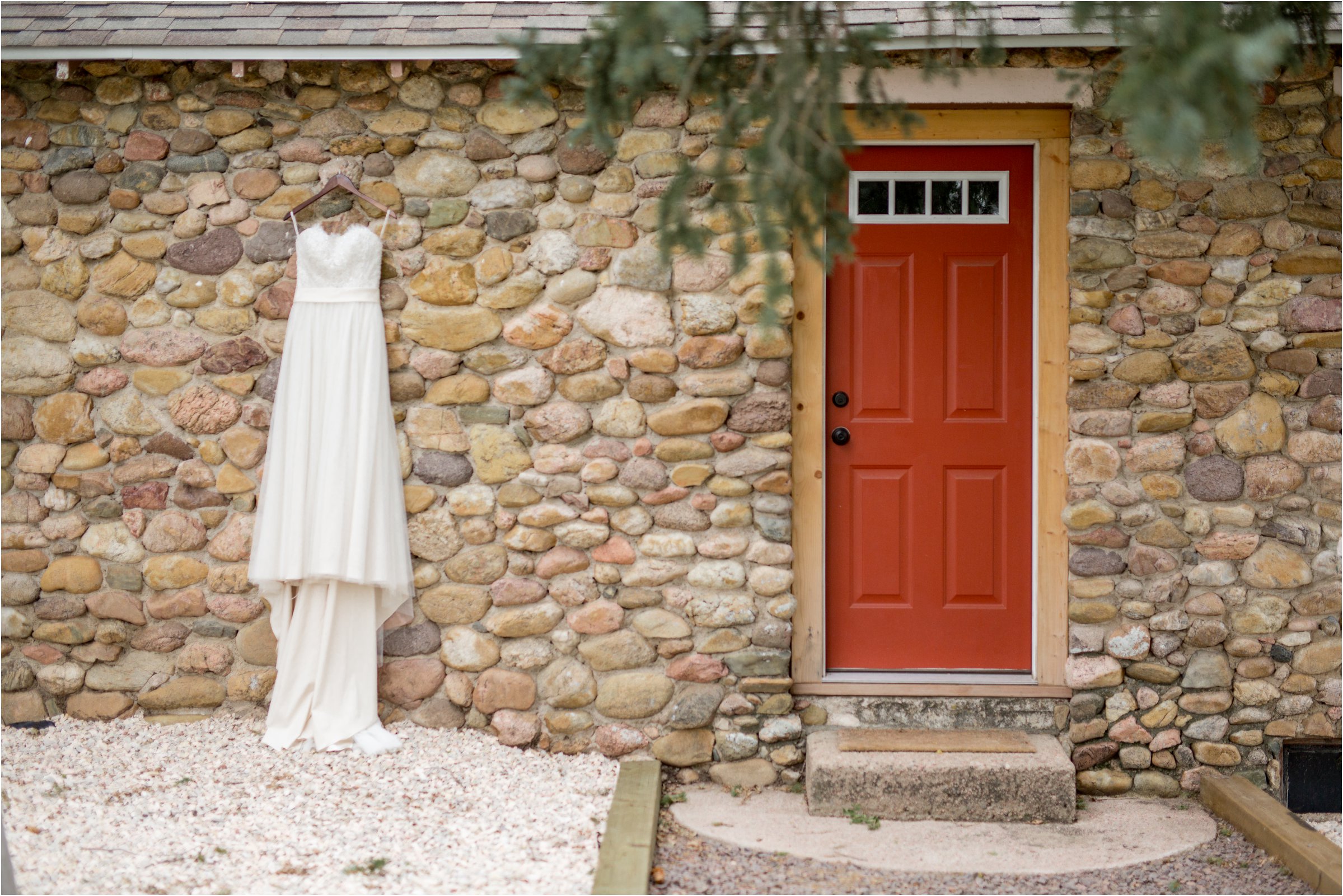 the bride's dress hanging on the stone wall of the bride and groom's house in the country