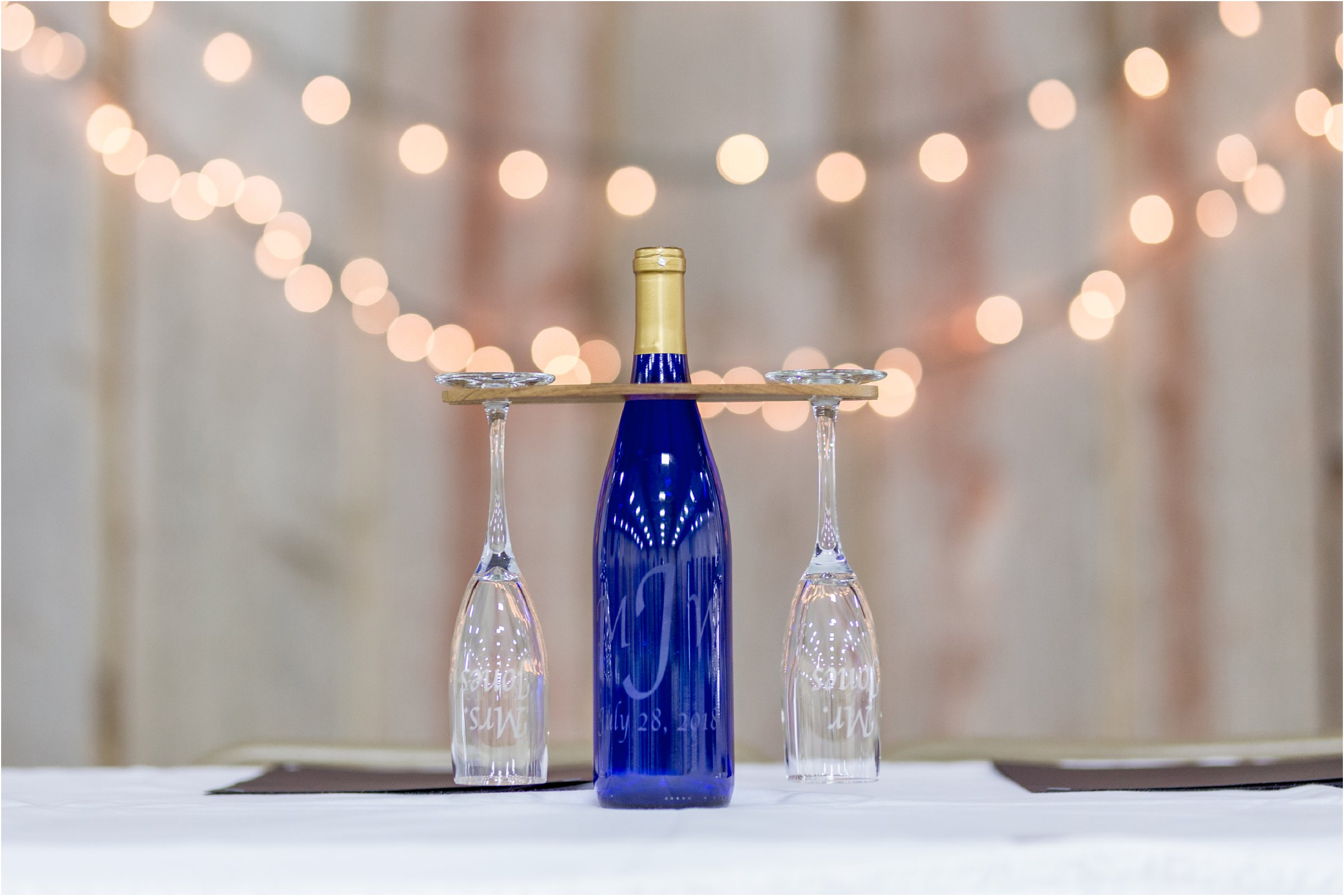 bride and groom's personalized champage glasses in front of bokeh lights