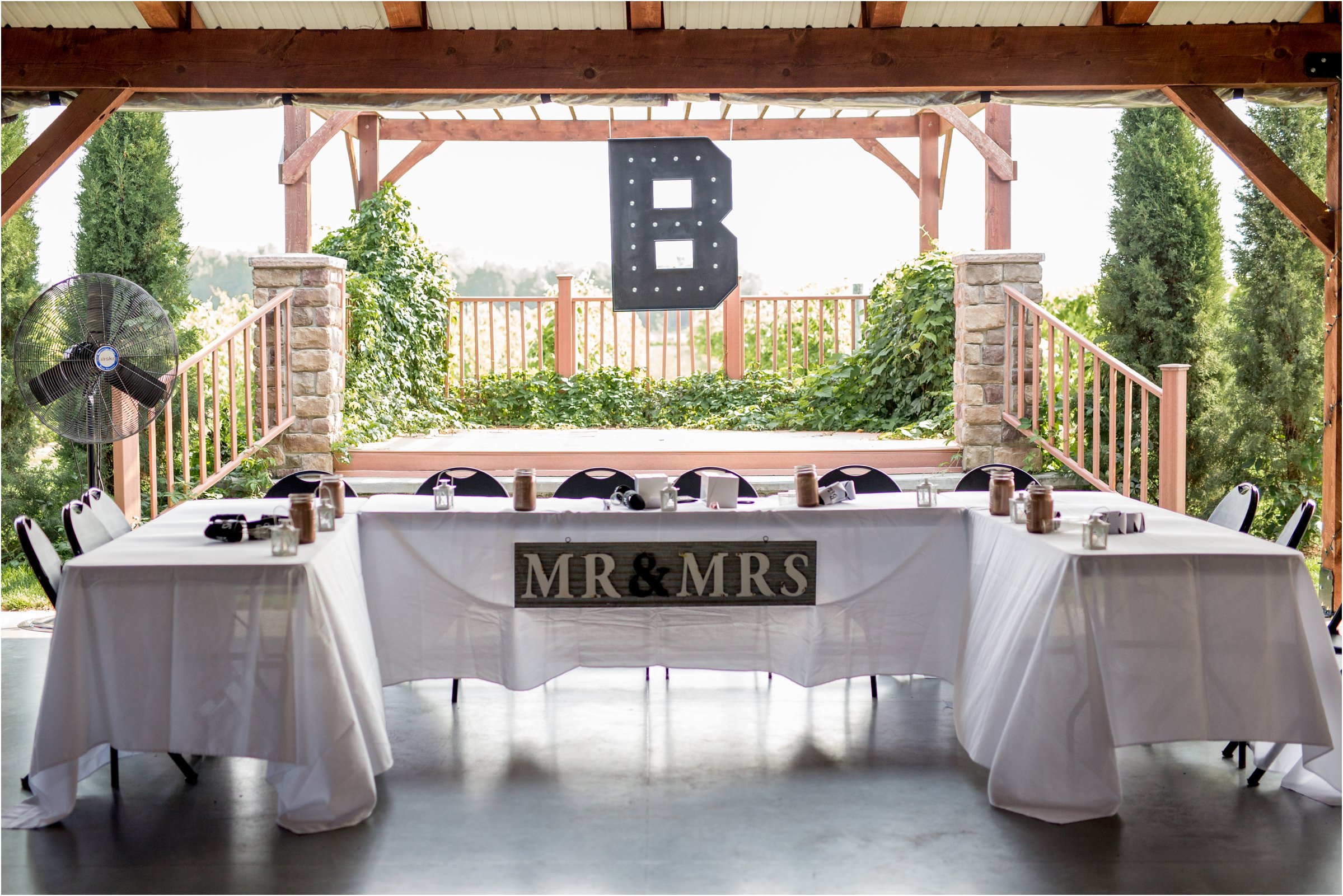 the head table with a large lit letter b placed above with a mr. and mrs. sign