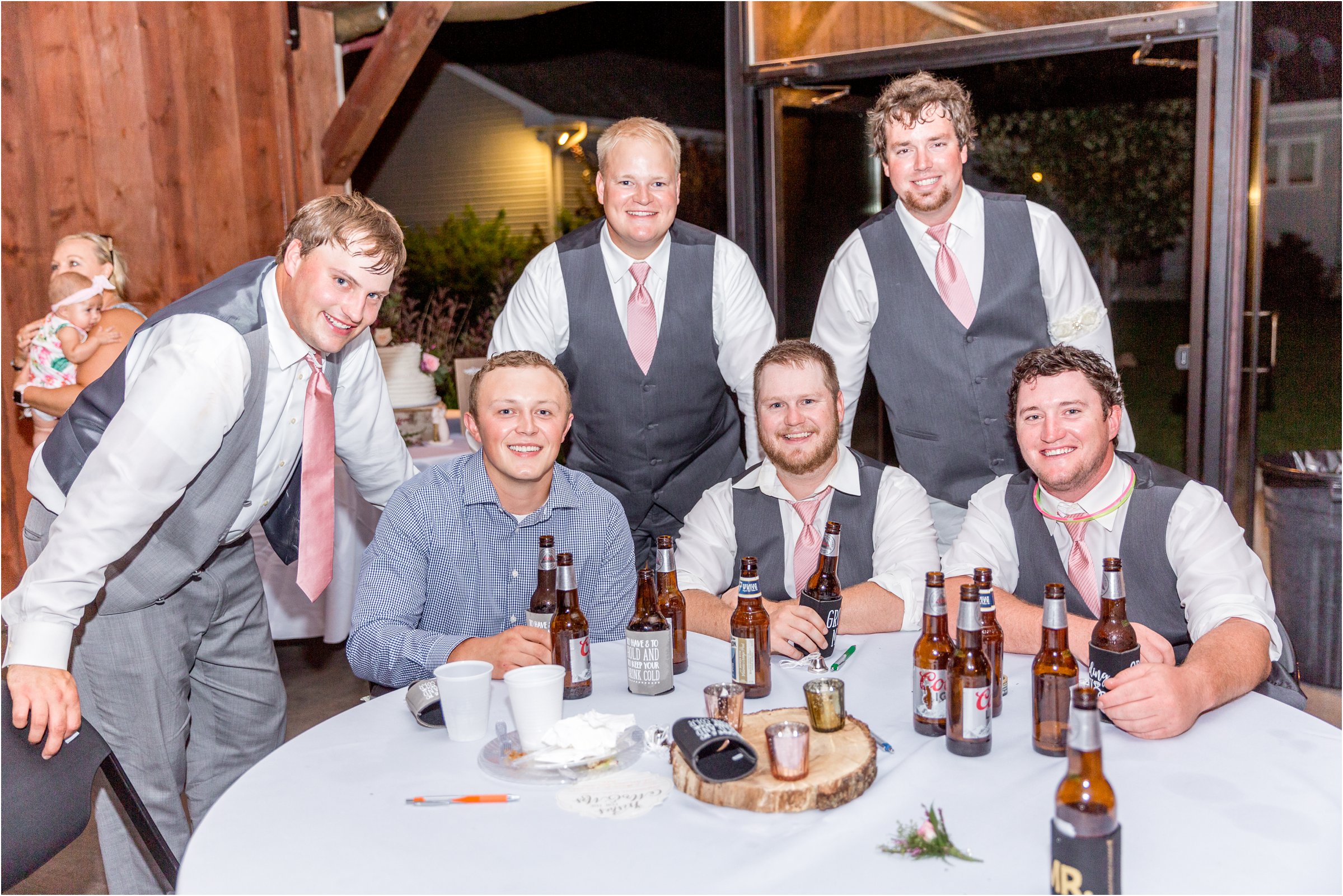 groom poses for a photo with a group of guy friends around a table