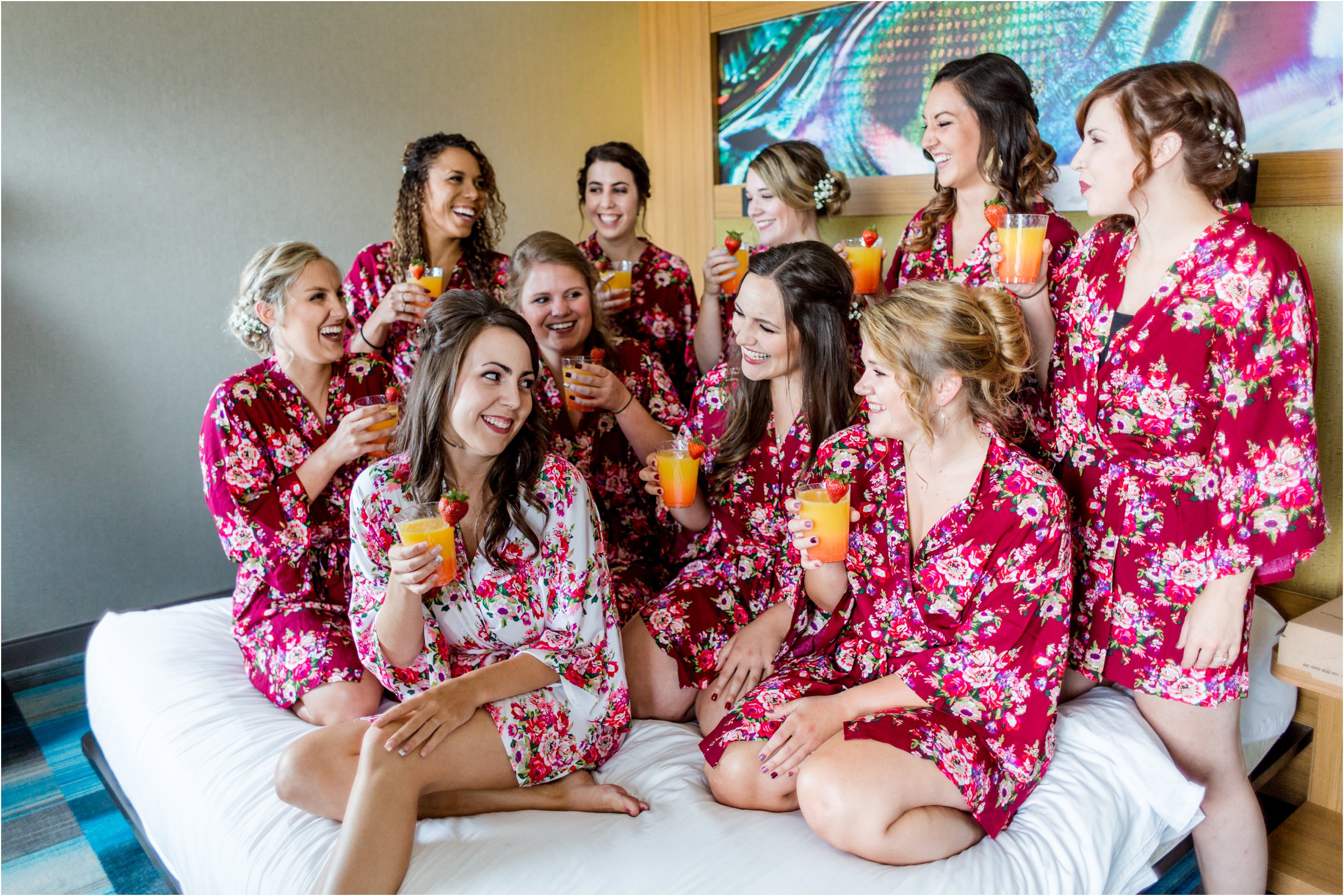 bridesmaids drink mimosas together on hotel bed