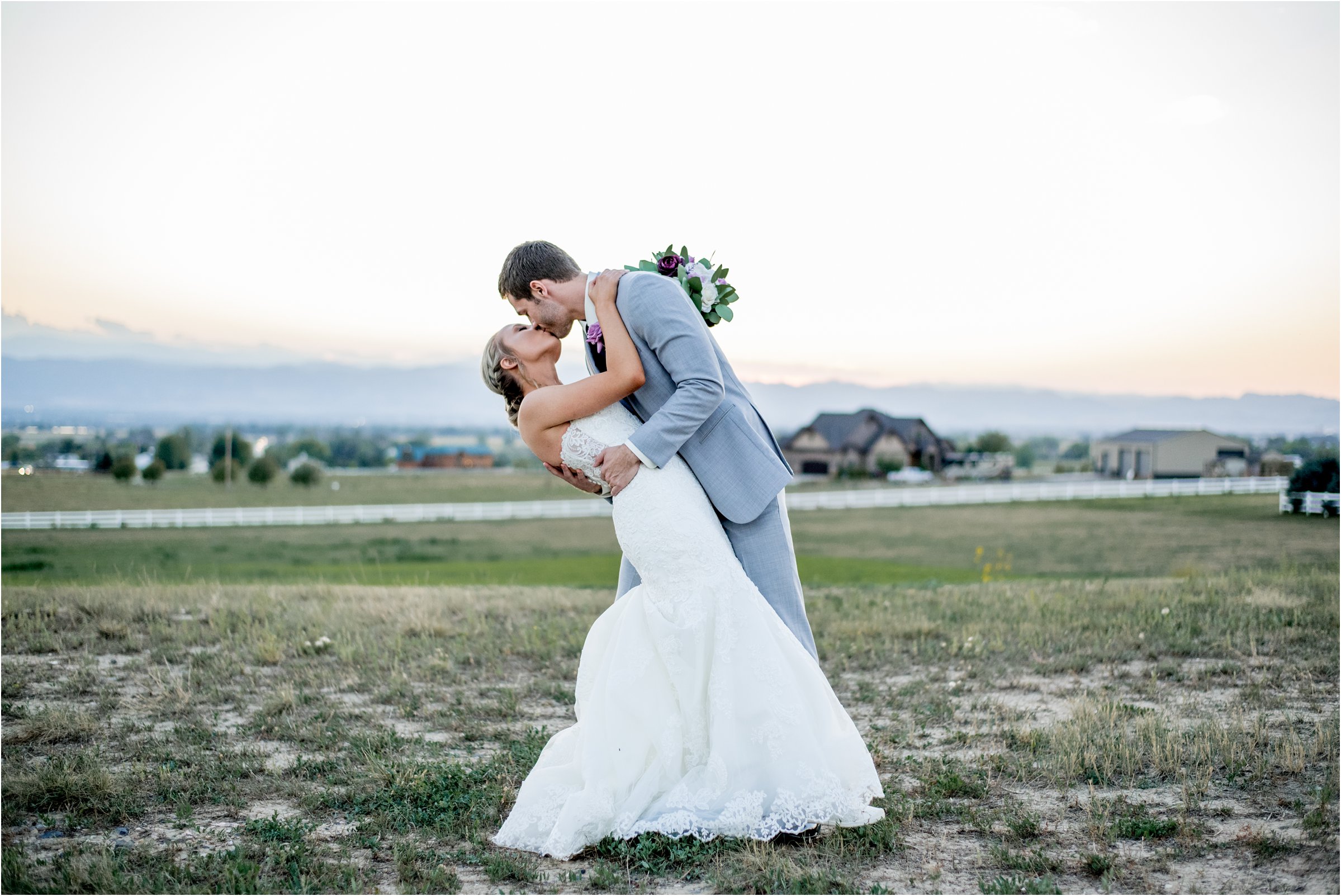 groom dips bride for a kiss in front of mountain range after their ceremony