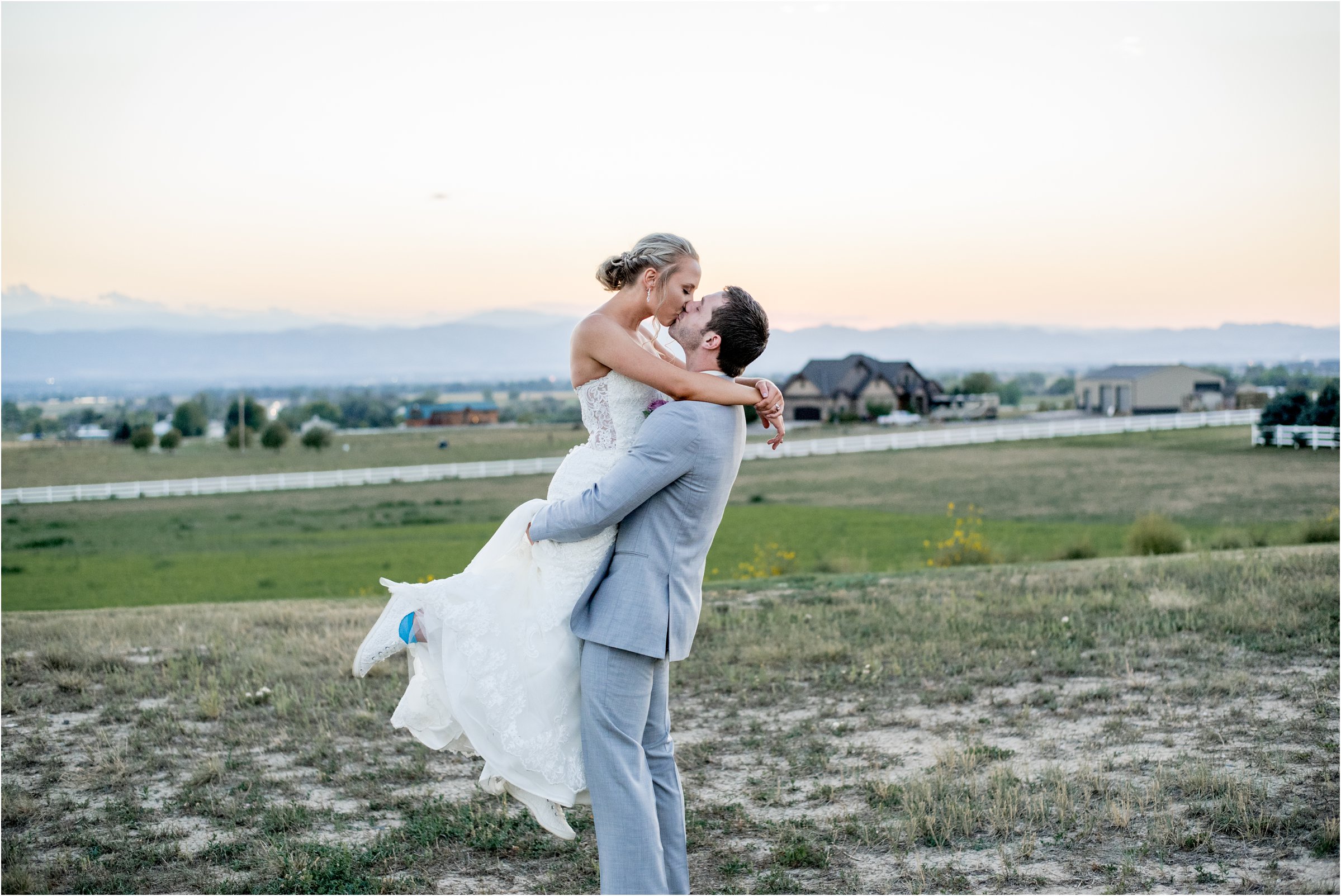 groom lifting bride up in the the air for a kiss with a mountain range in the background
