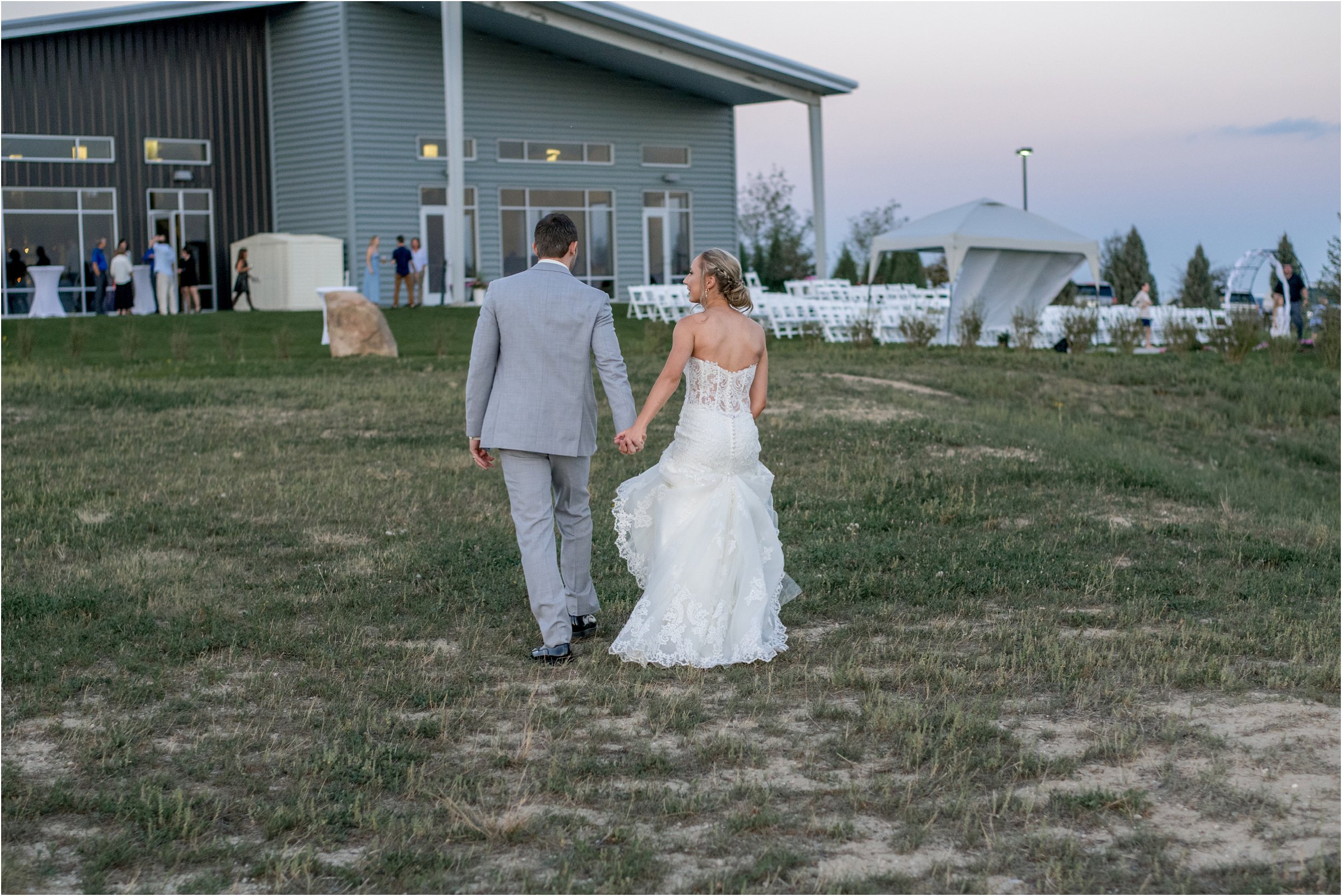 bride and groom walk away from camera toward their reception after finishing their photos