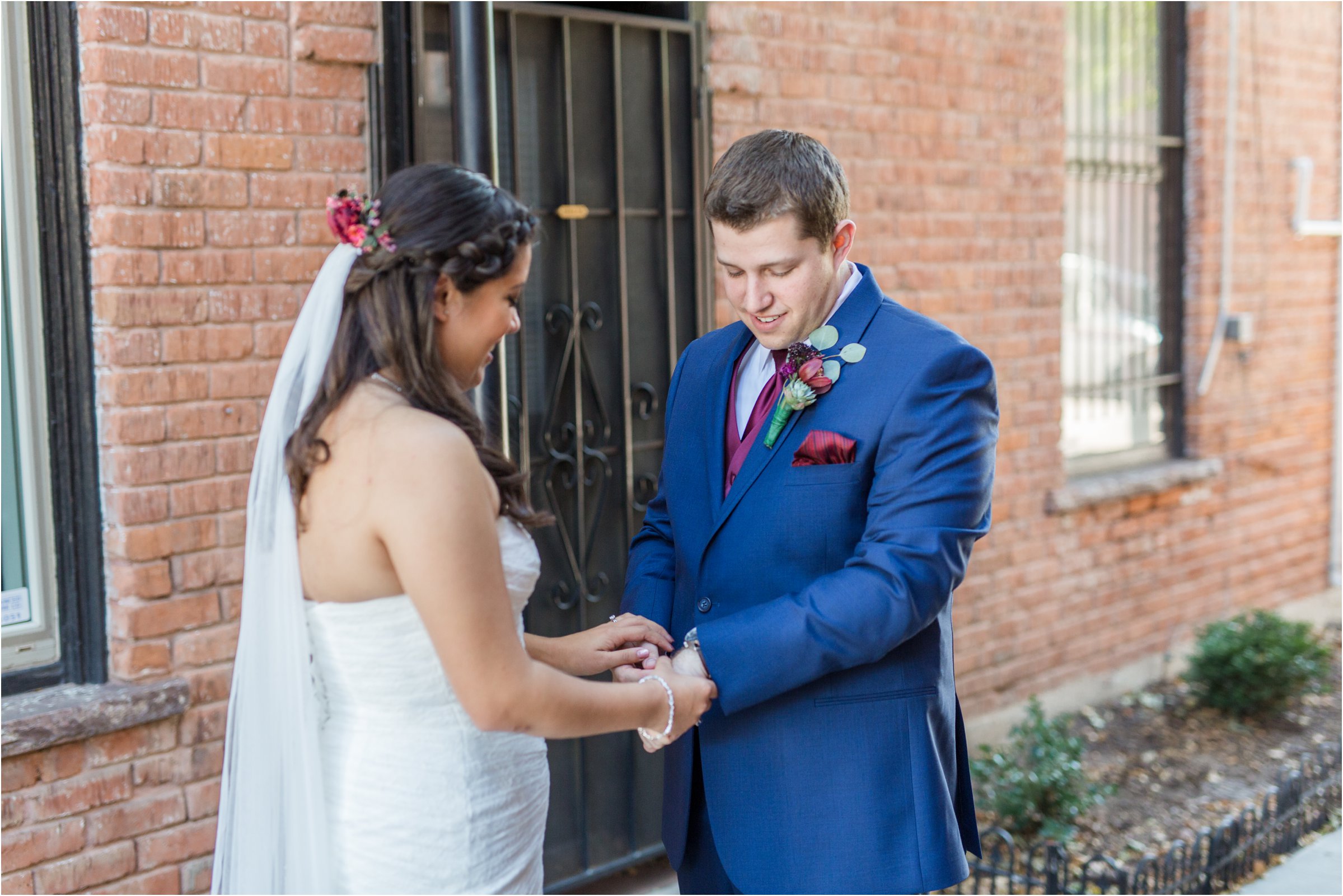 groom looks at brides hands right after first look in alleyway behind the loft music venue