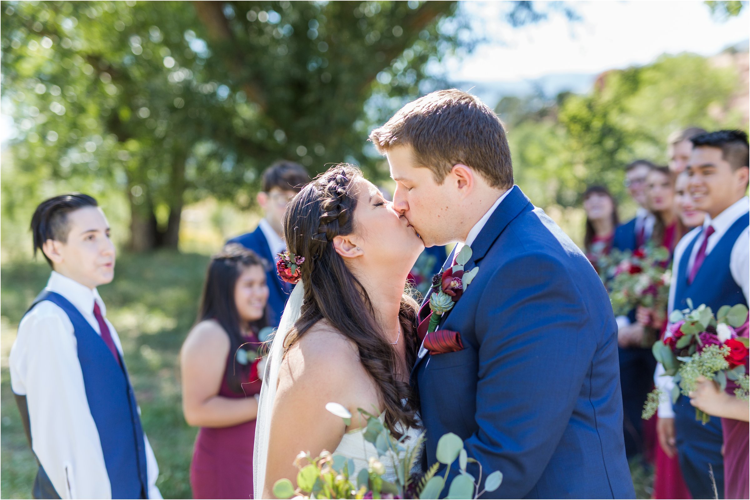 bride and groom kiss together in front of bridal wedding party before ceremony