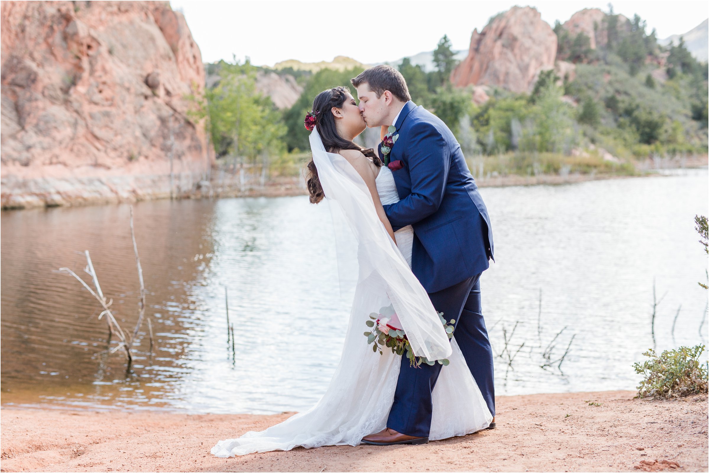 Bride and groom kiss in front of a lake in Red Rock Canyon Open Space