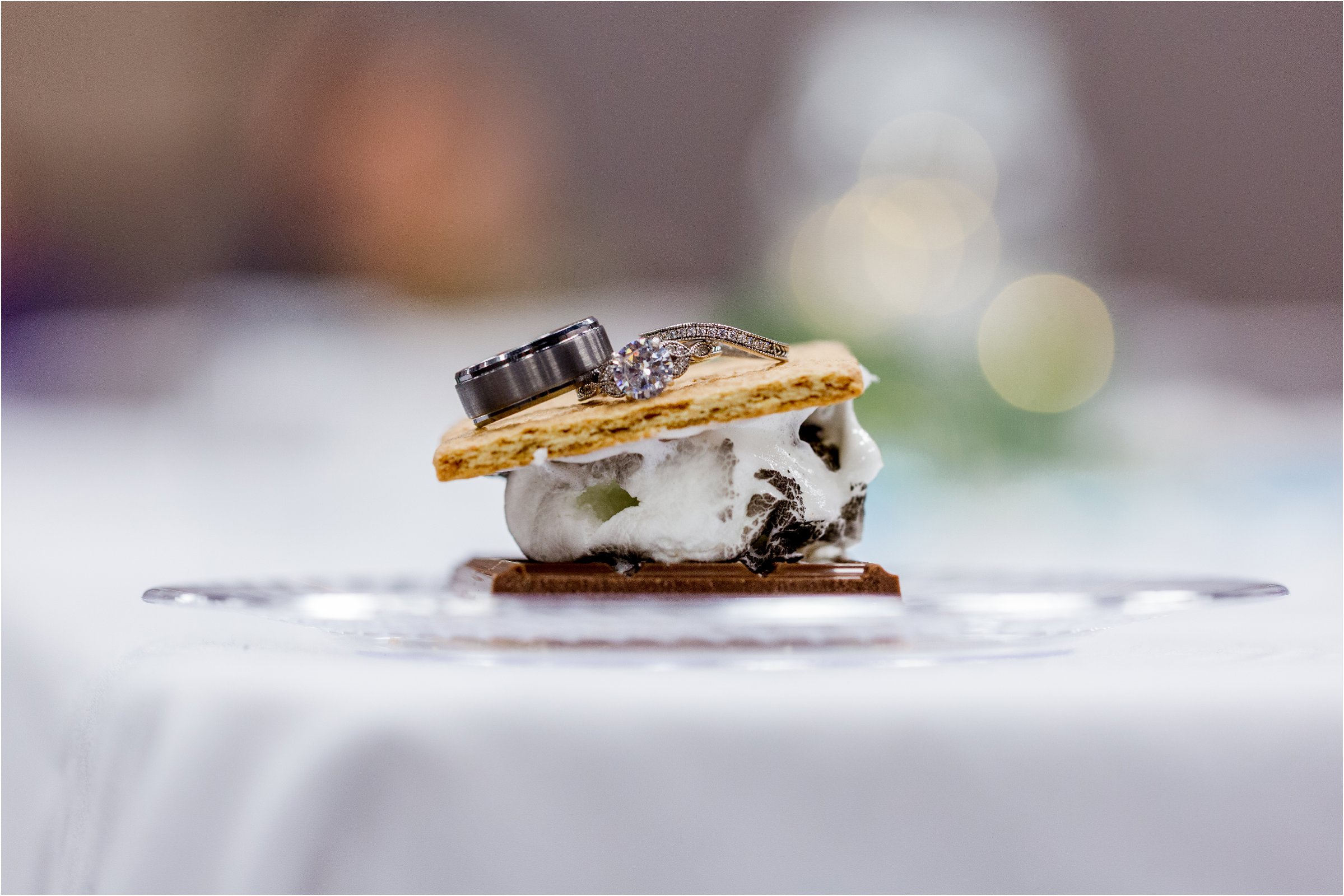 bride and groom's wedding rings placed on a smore with lights in the background