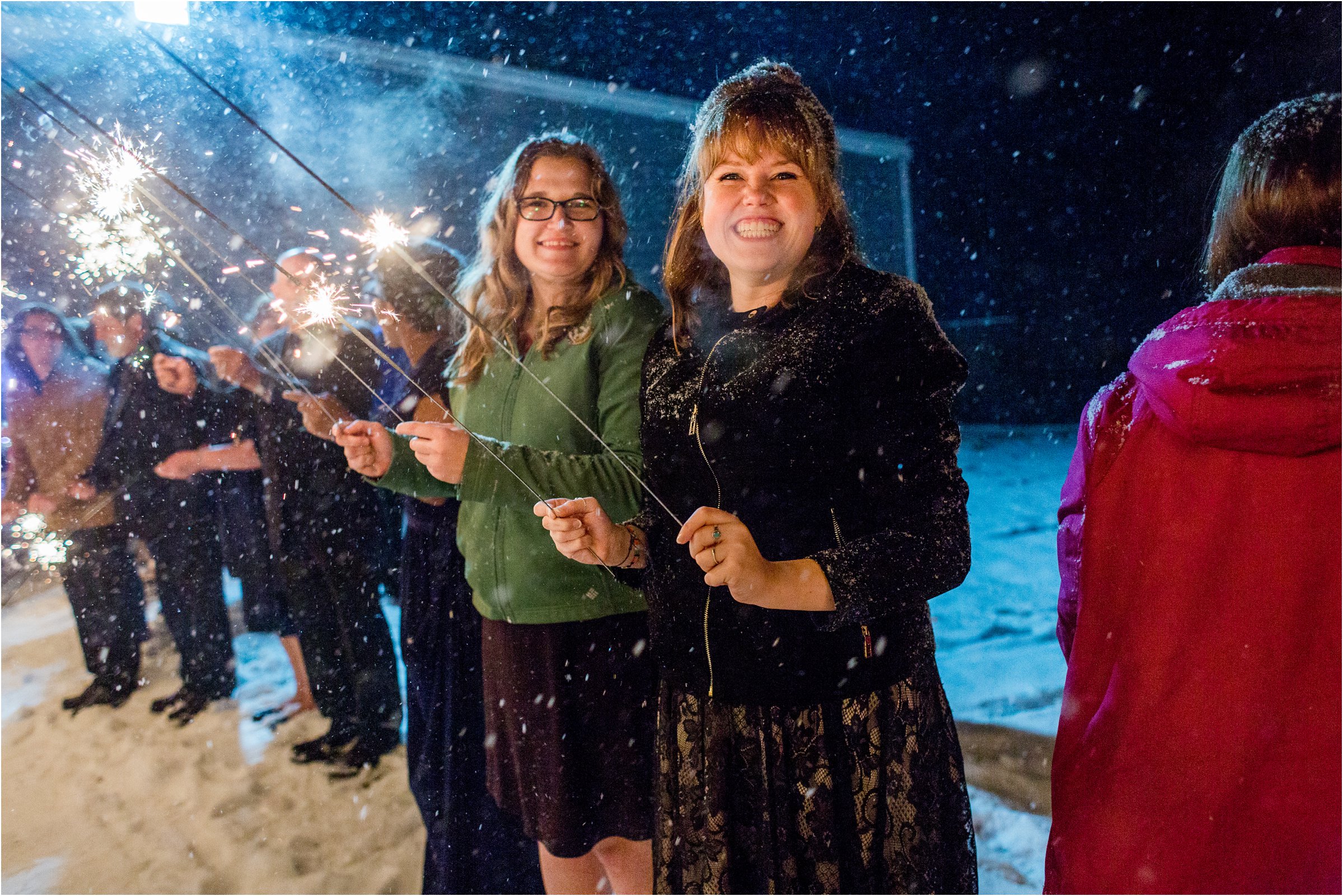 wedding guests holding sparklers waiting for the bride and groom to make their exit in the snow