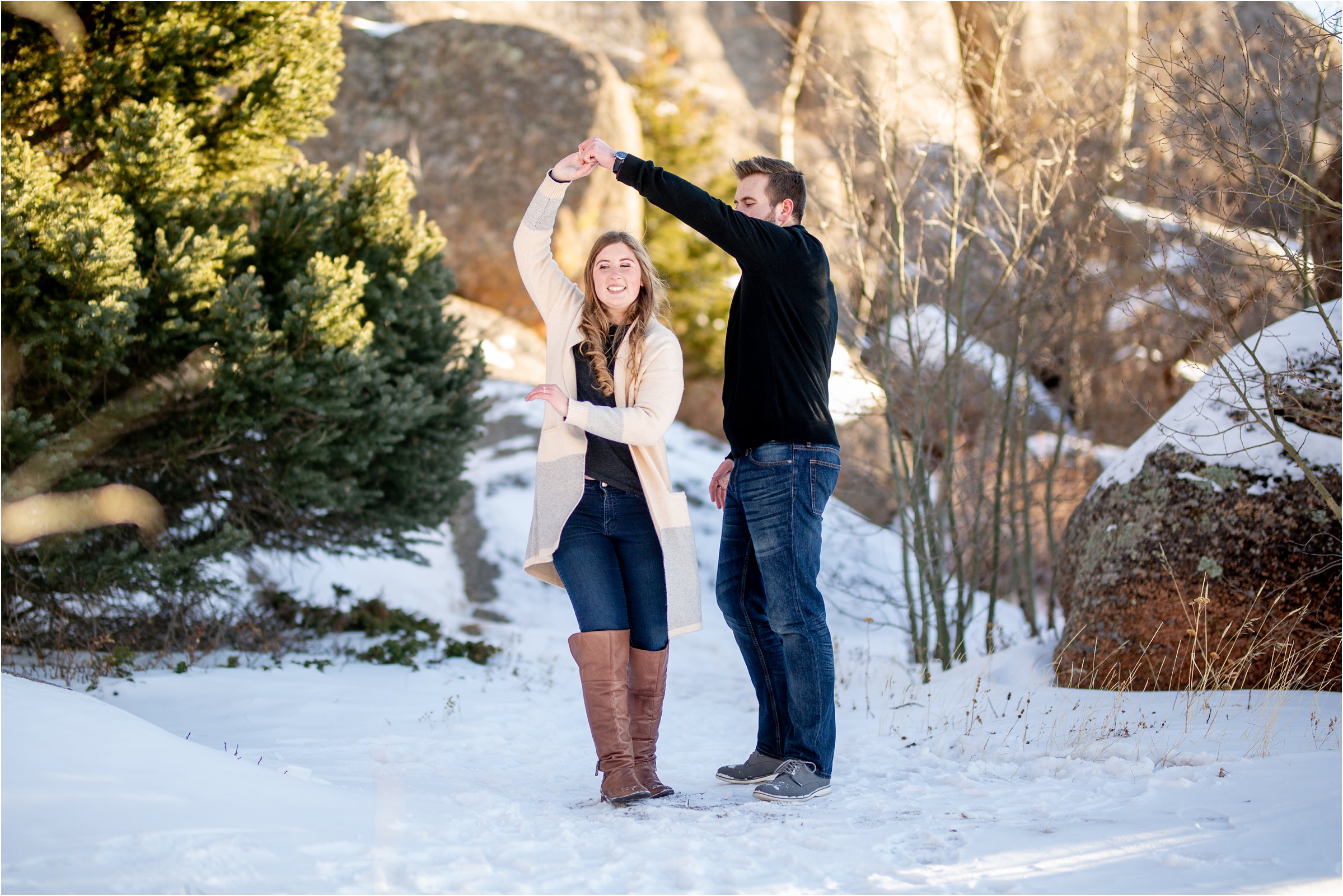 Engaged couple dancing in the snow with rocks in the background for their cheyenne engagement session