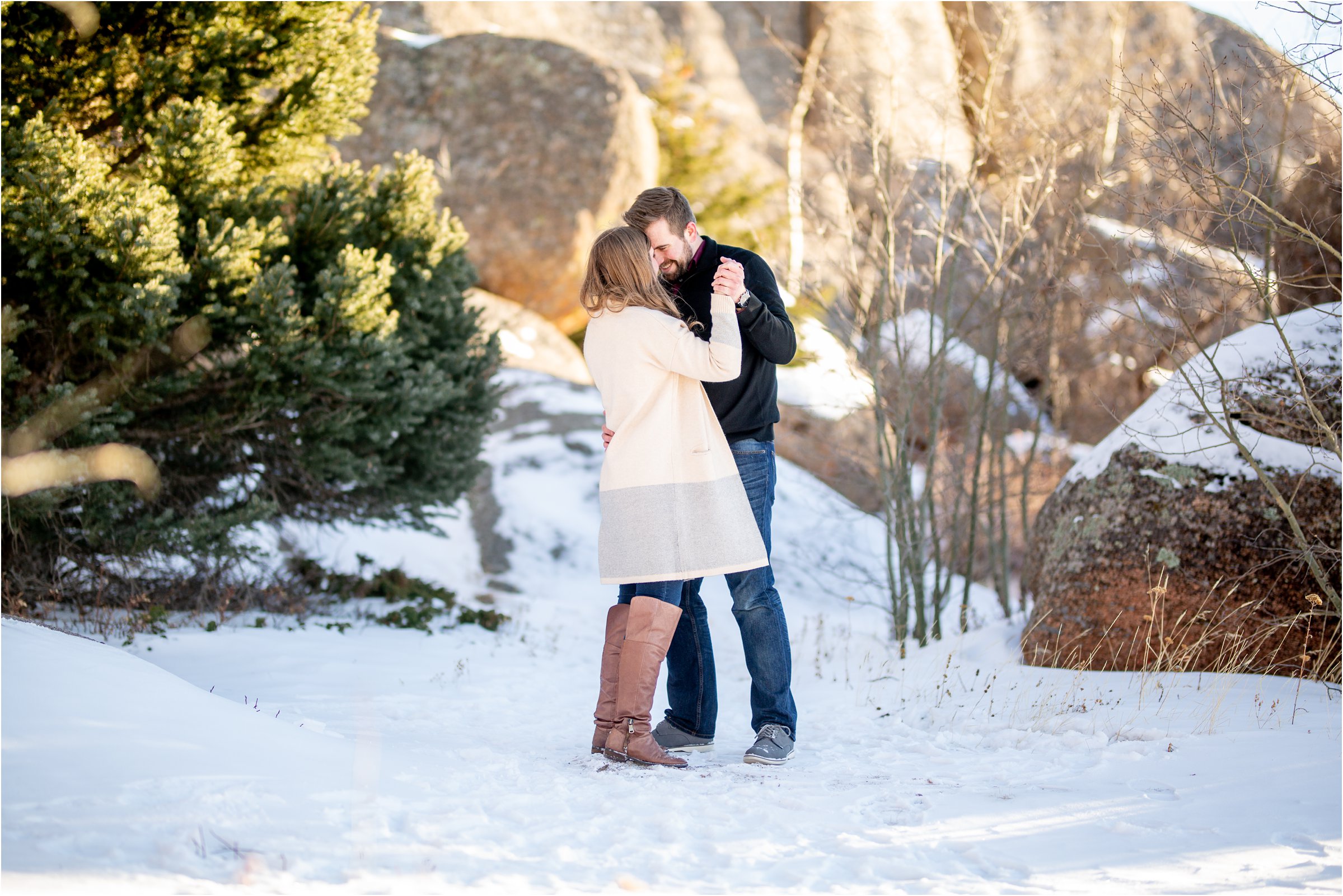 Engaged couple dancing in the snow together with Vedauwoo in the background