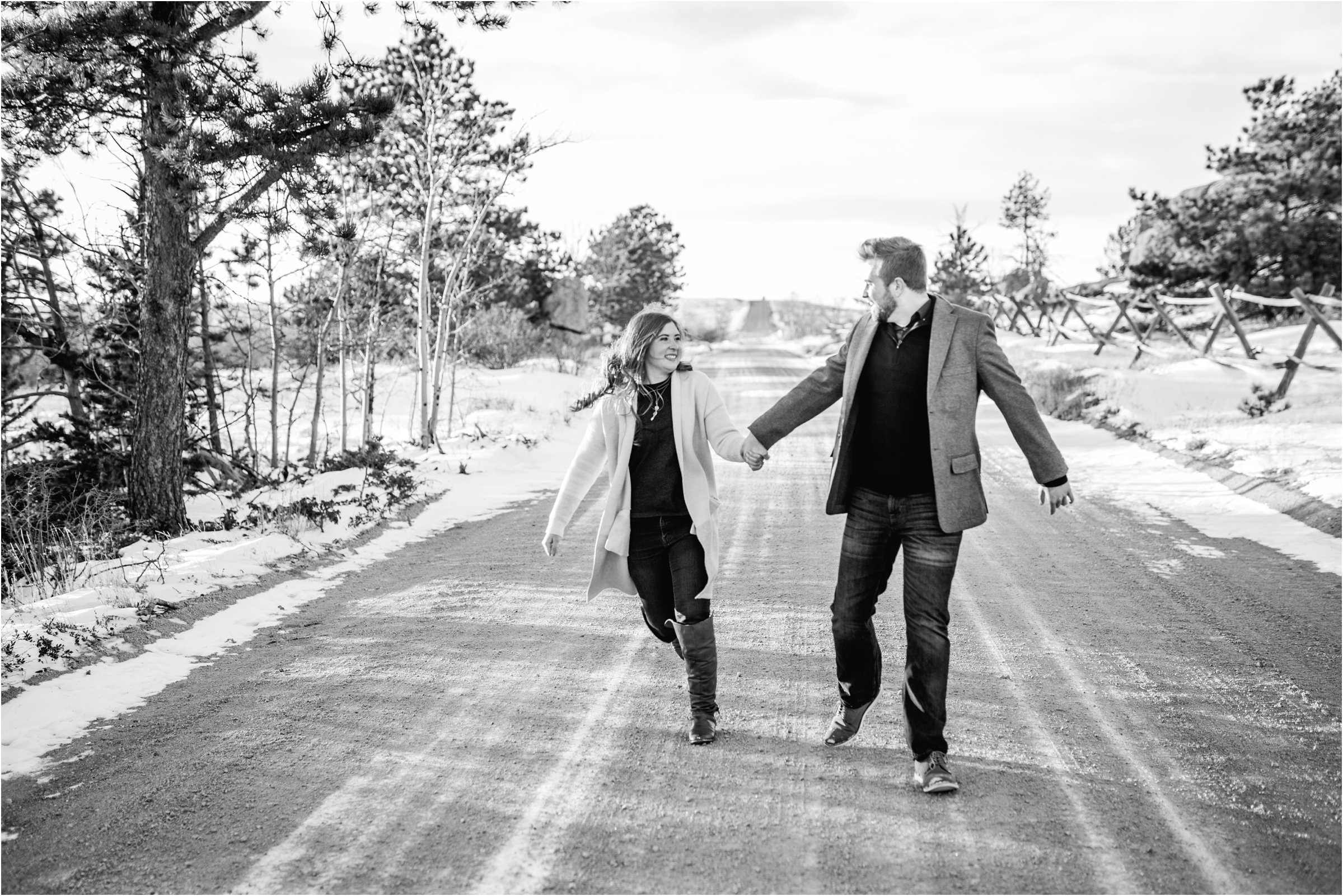 engaged couple running down gravel road together holding hands and smiling for their cheyenne engagement session