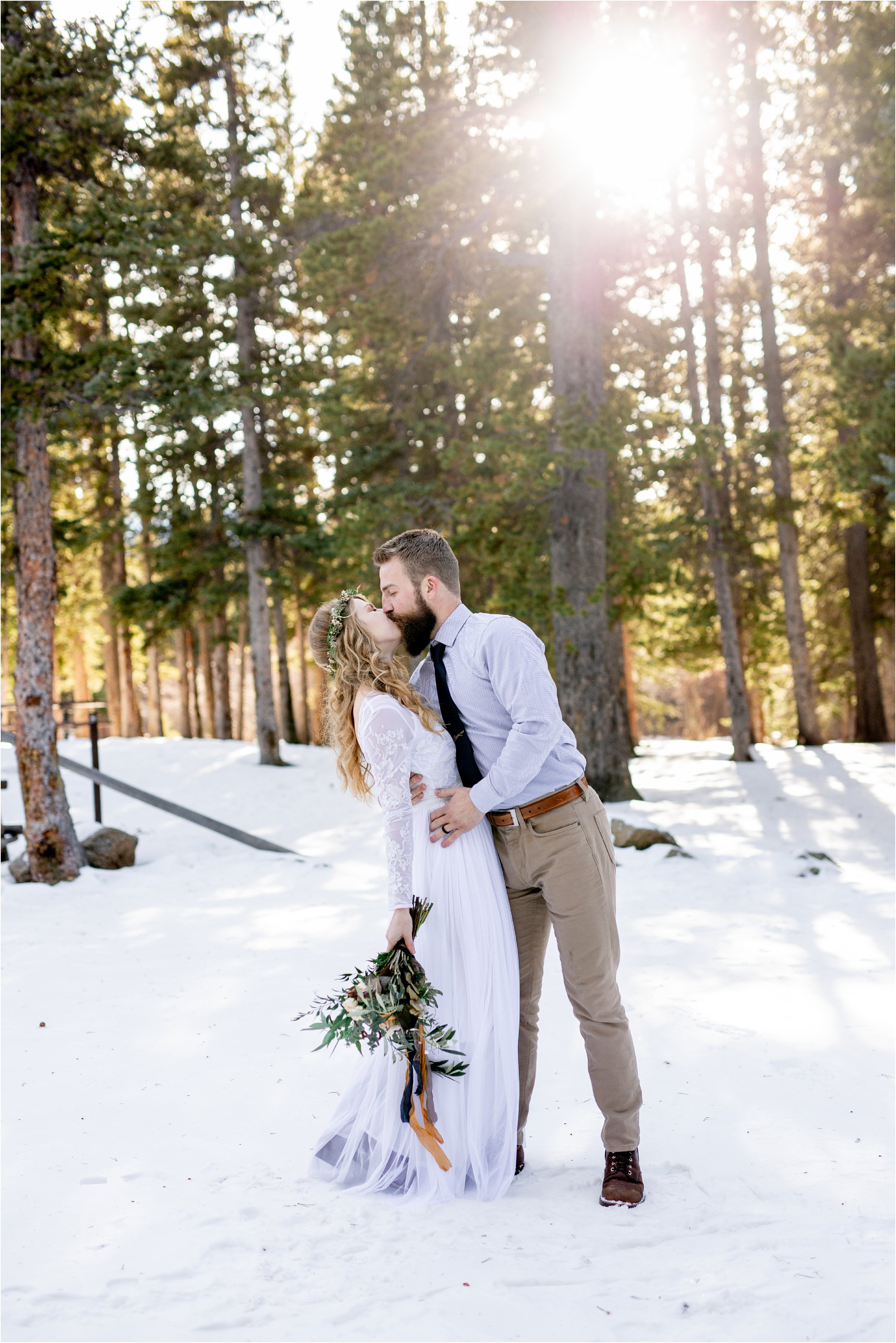 groom kissing his bride with sun coming through the trees above for their Denver elopement