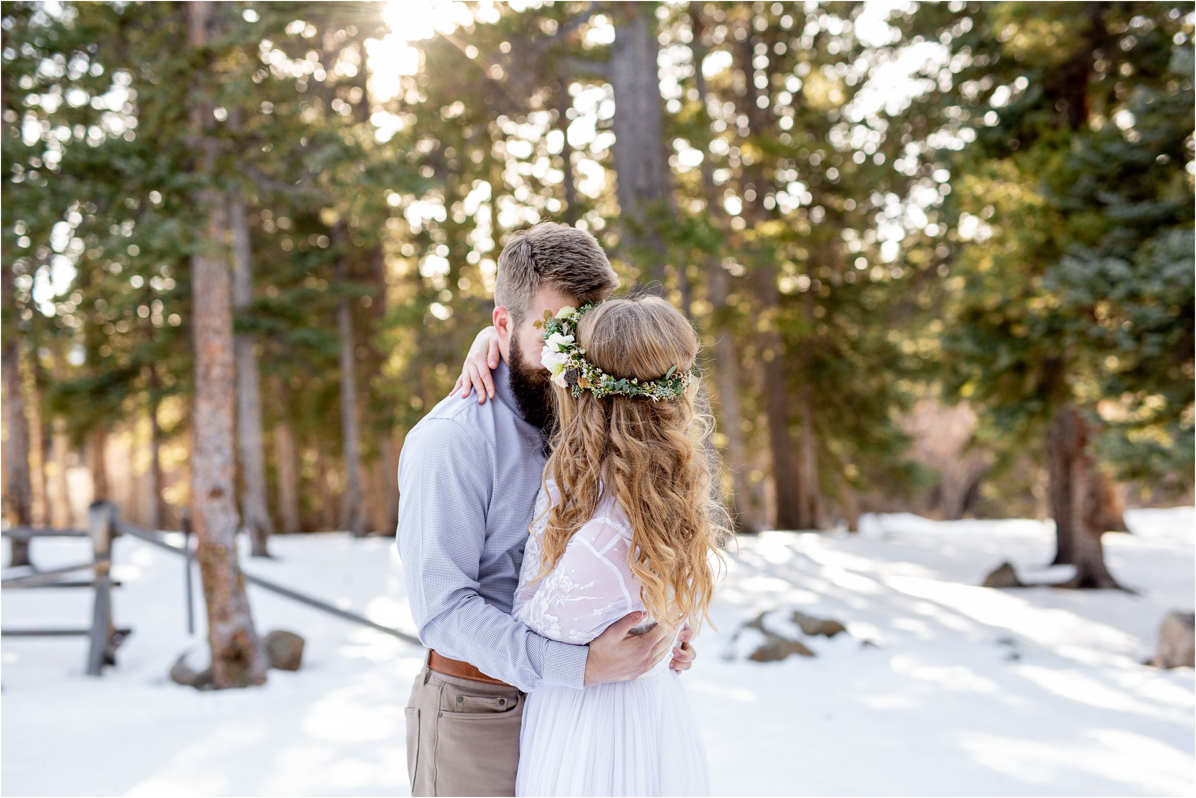 Bride and groom in front of trees snuggling in wedding attire