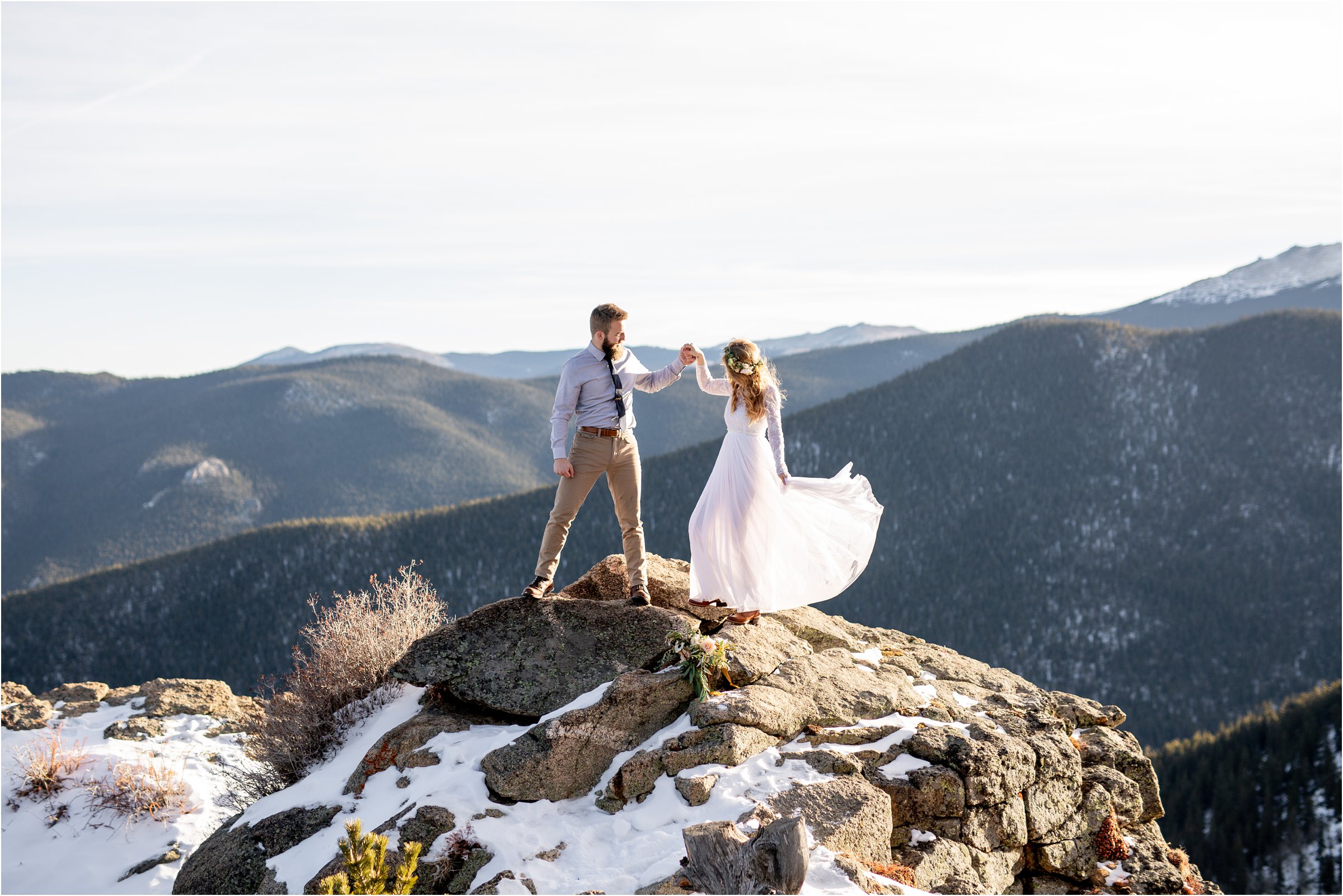 Bride and groom on mountain top swirling wedding dress