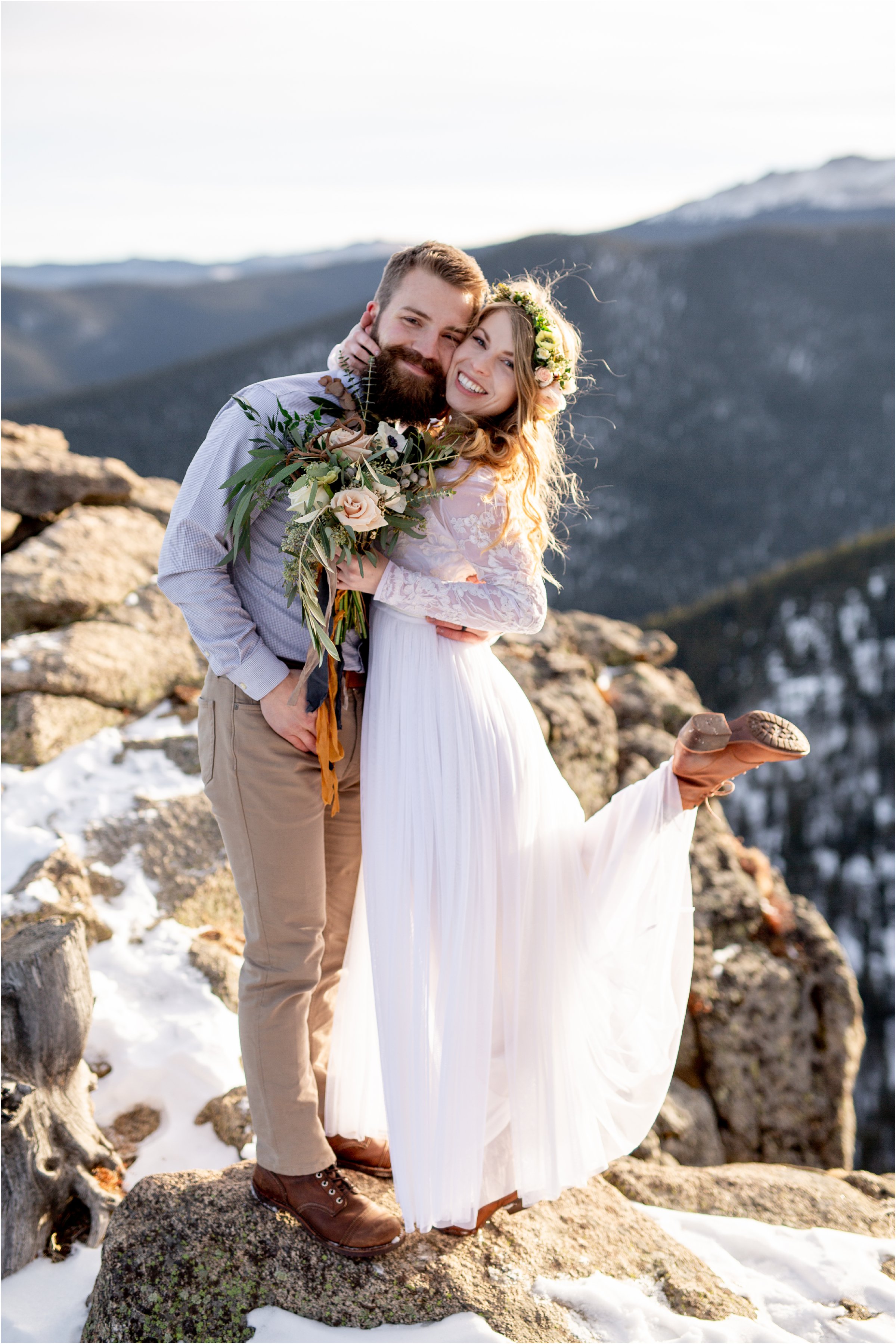 Bride and Groom looking at camera in wedding attire while bride's foot is popped in the air