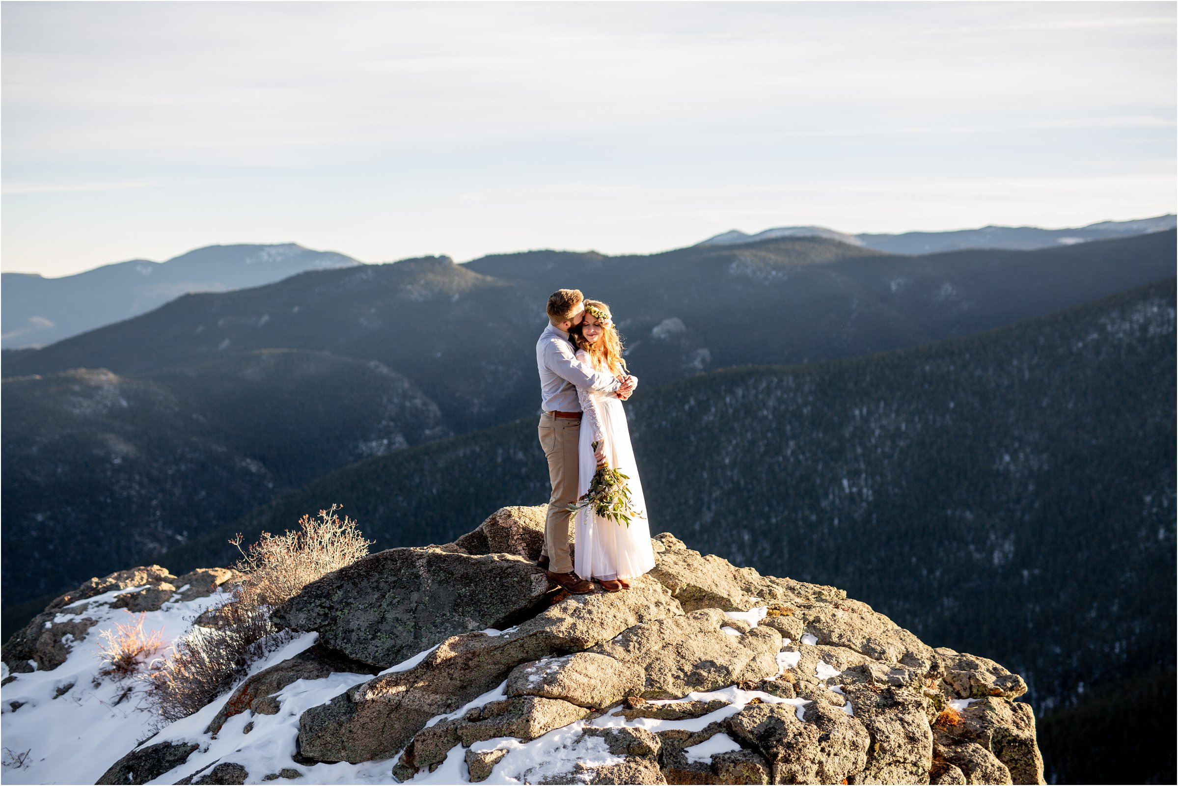 Bride and groom together on a mountain top snuggling faces