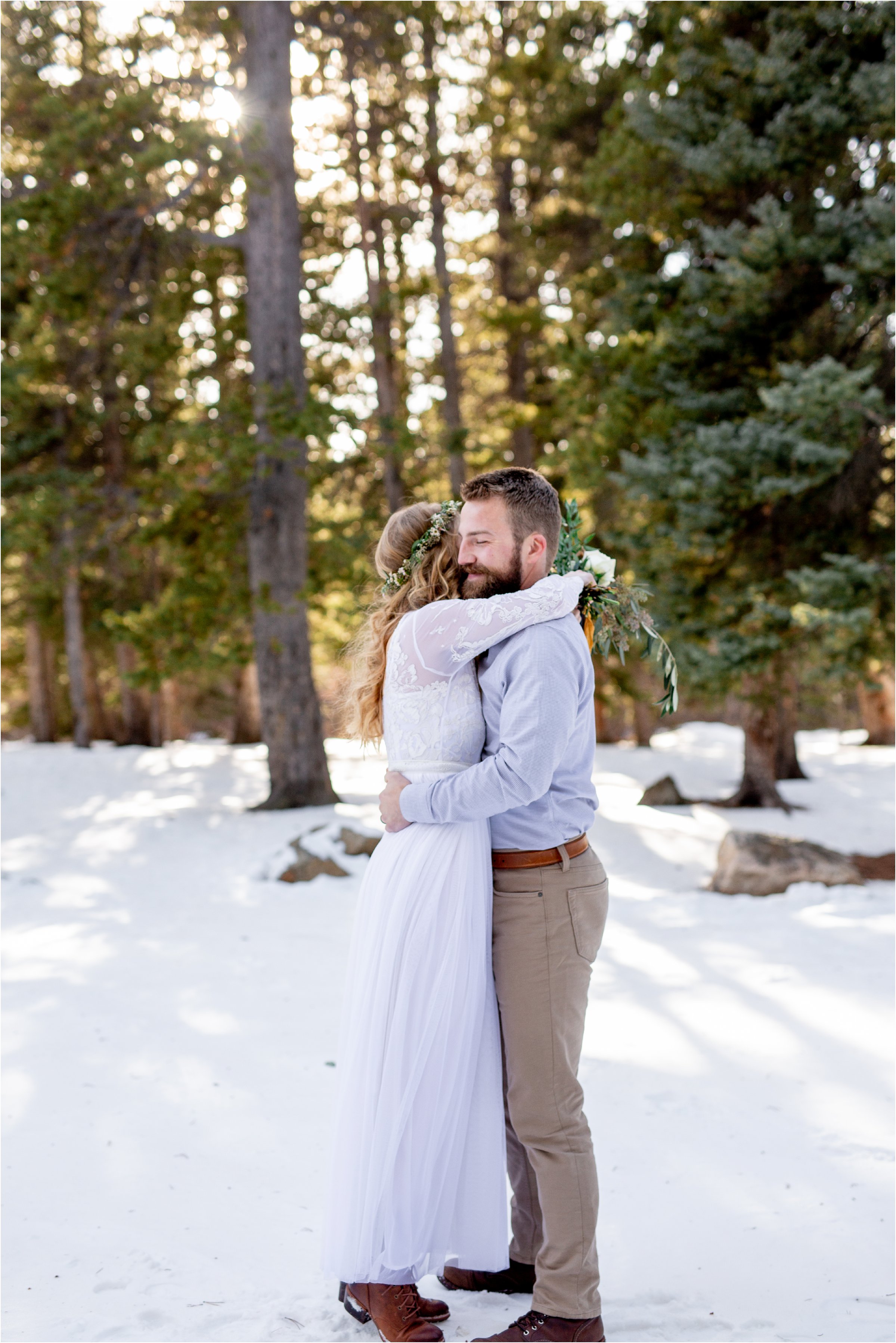 bride and groom hugging in evegreen forest with sun shining through the trees for their Denver elopement