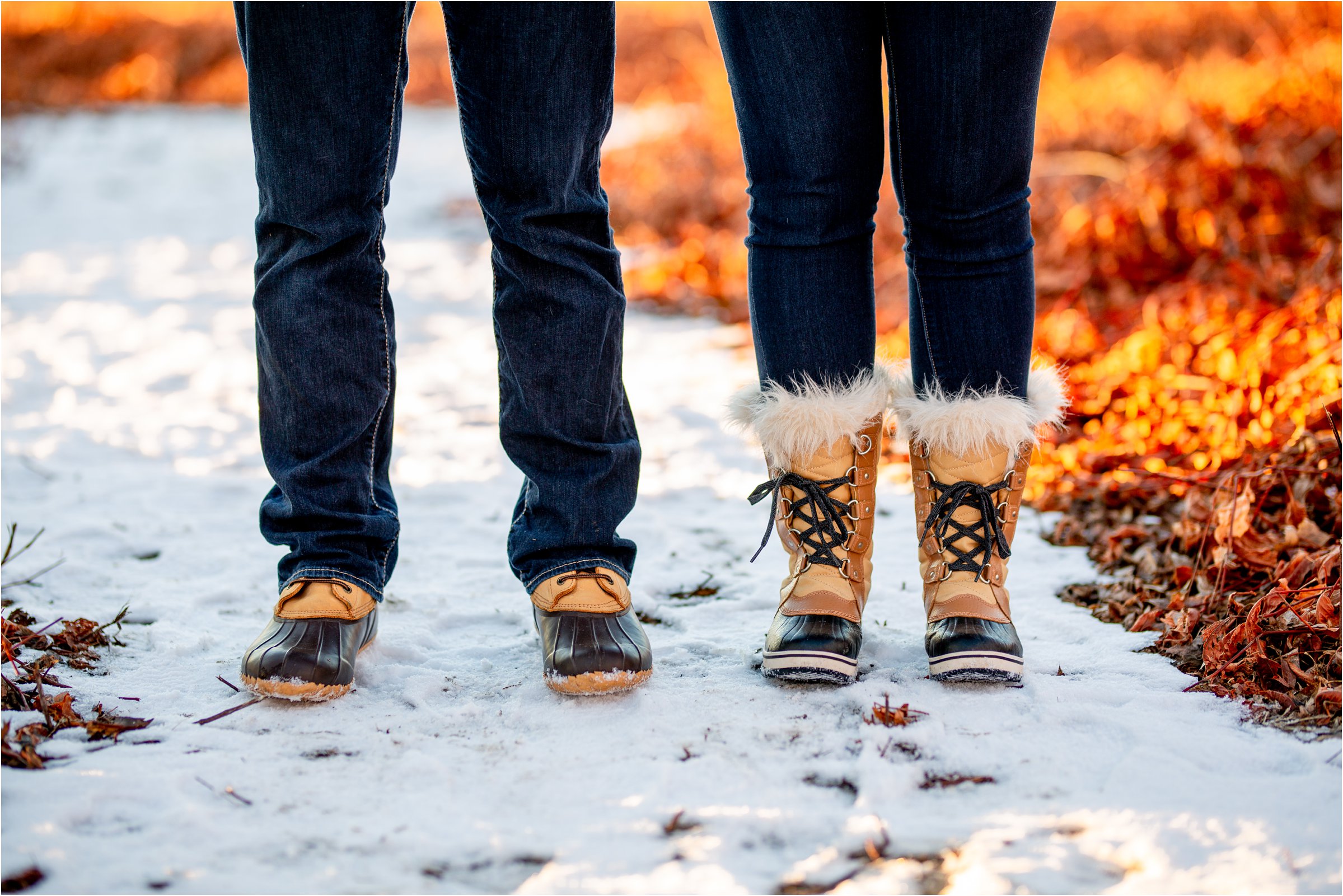 Couple with duck boots in the snow with a vibrant orange backdrop