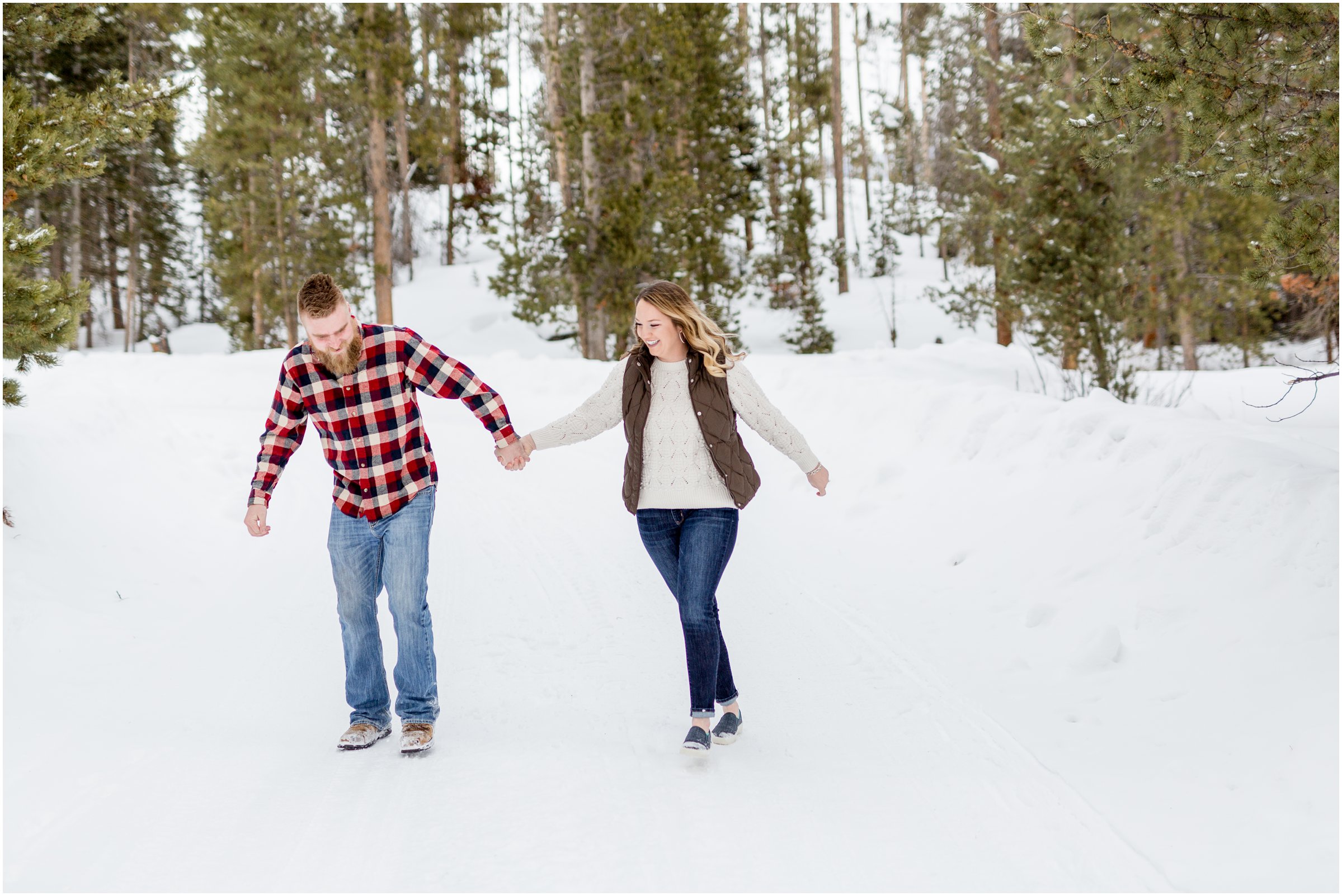 bride and groom run towards the camera with snow on the ground and trees in the background for their engagement session with a Grand lake wedding photographer