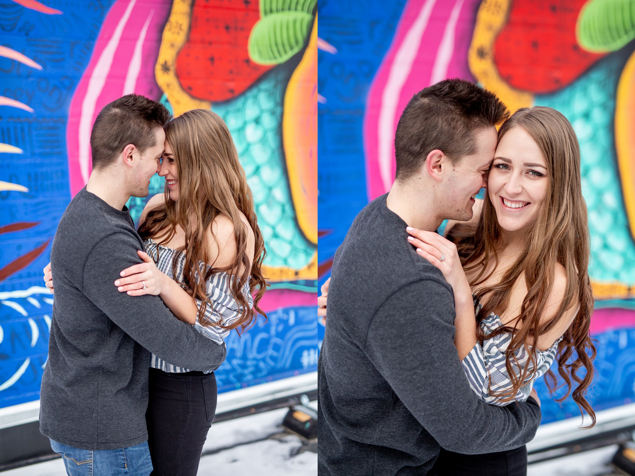 engaged couple in front of colorful wall snuggling together 